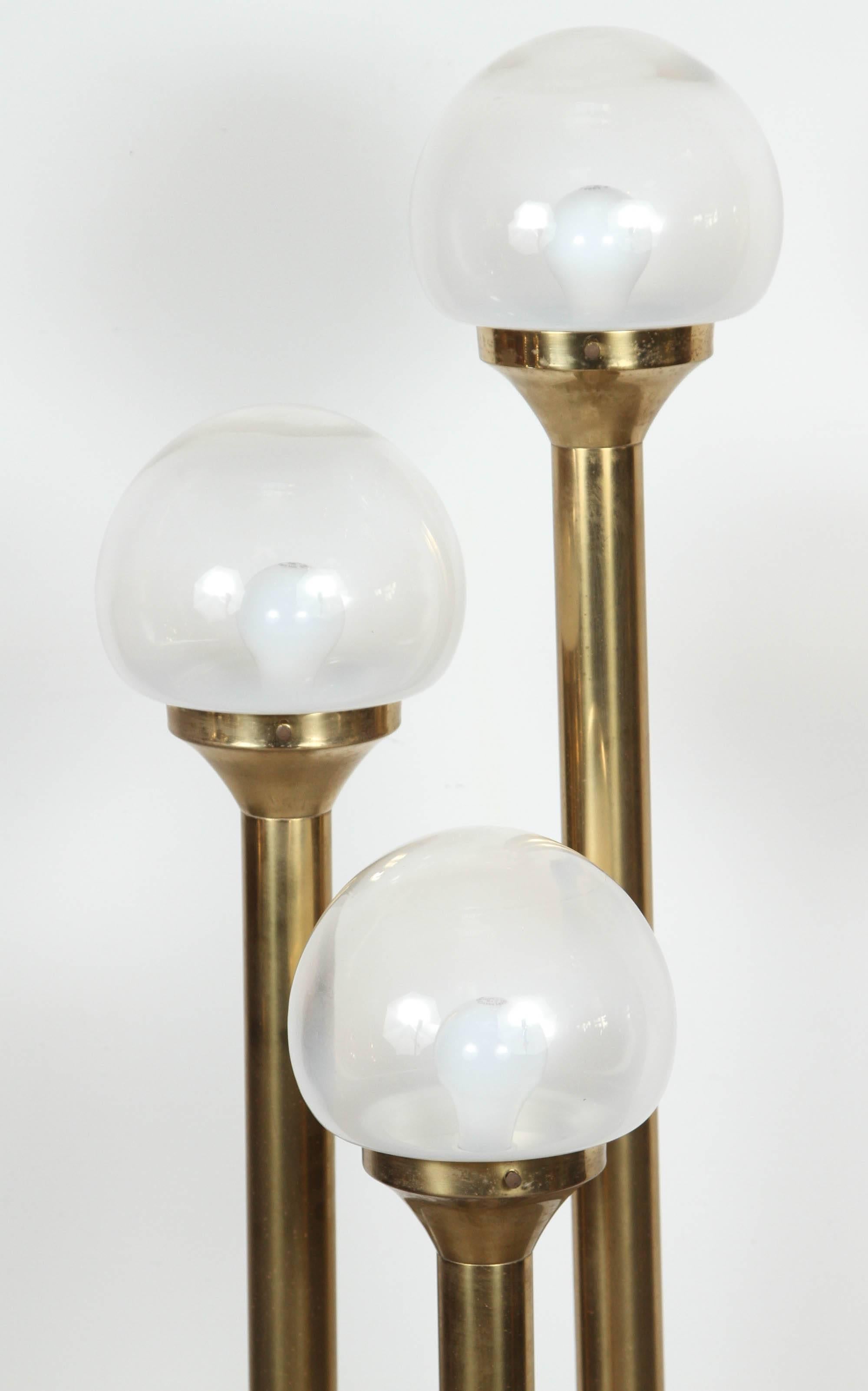 Mid-Century Modern, vintage Italian brass floor lamp with three tubular supports, each holding a handblown Murano-glass globe that is solid white at base graduating to clear at the top. 
Overall dimensions including globes 11.5" W x 11.5"
