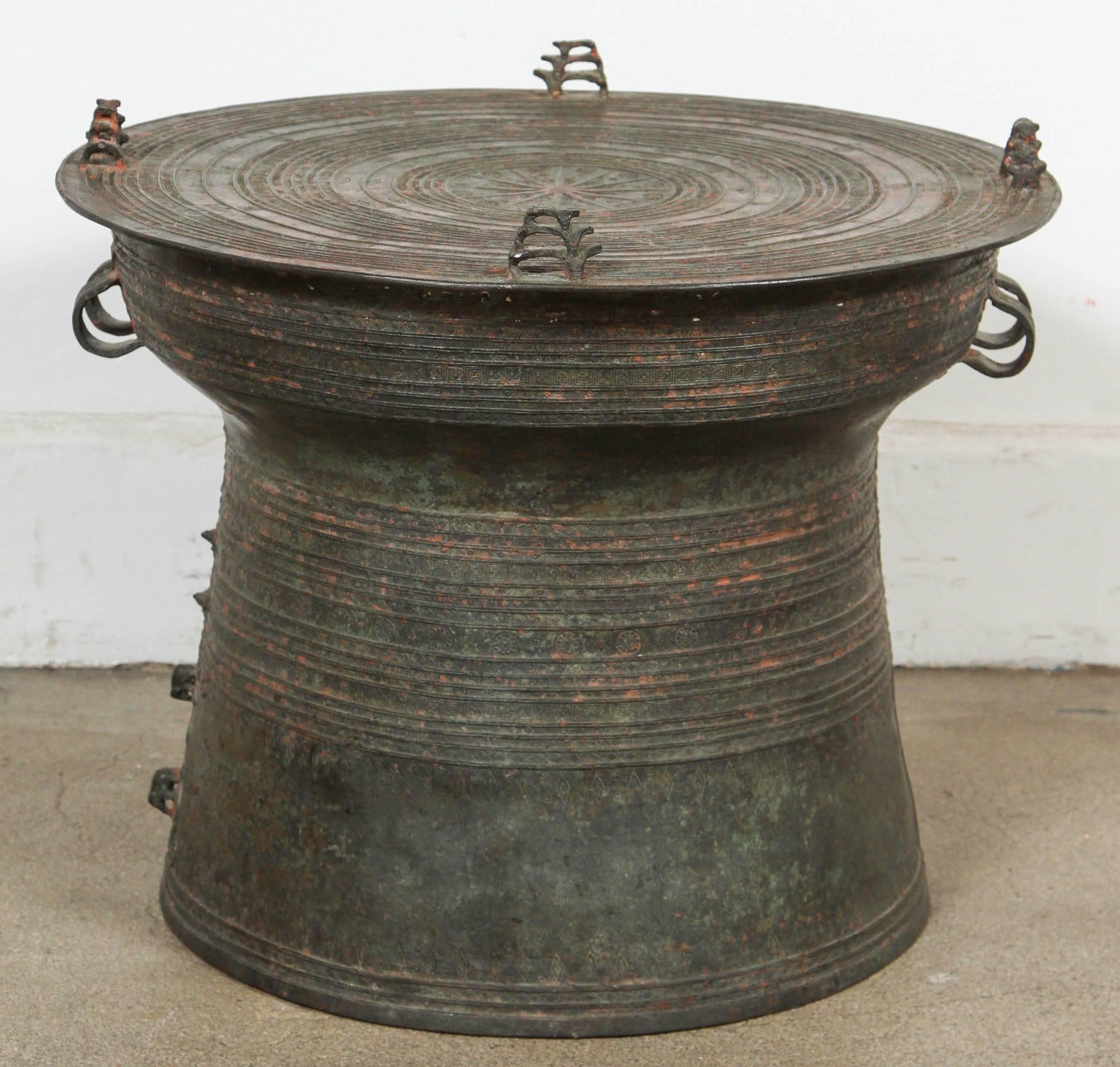 Asian cast bronze rain drum with the traditional intricate detailing and patterns carved all around both the body and the top.
The top is flat centered with a raised star surrounded by concentric geometric patterned bands and with raised triple