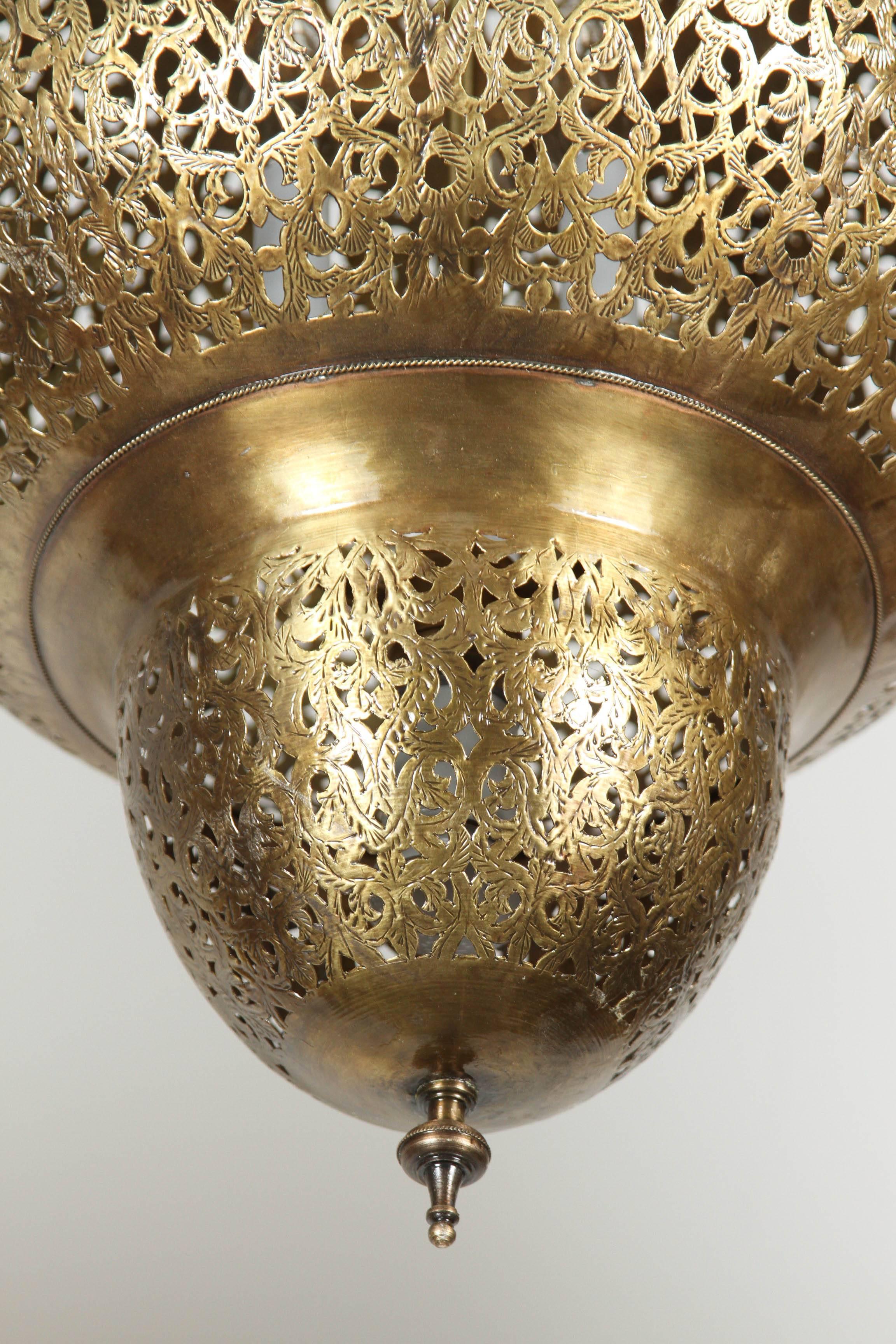 Large fabulous pierced Moroccan polished brass chandelier.
Handcrafted vintage Moroccan pierced filigree polished brass light fixture with a nice gold patina finish. The filigree designs in these pendant cast a pattern on the walls and ceiling when