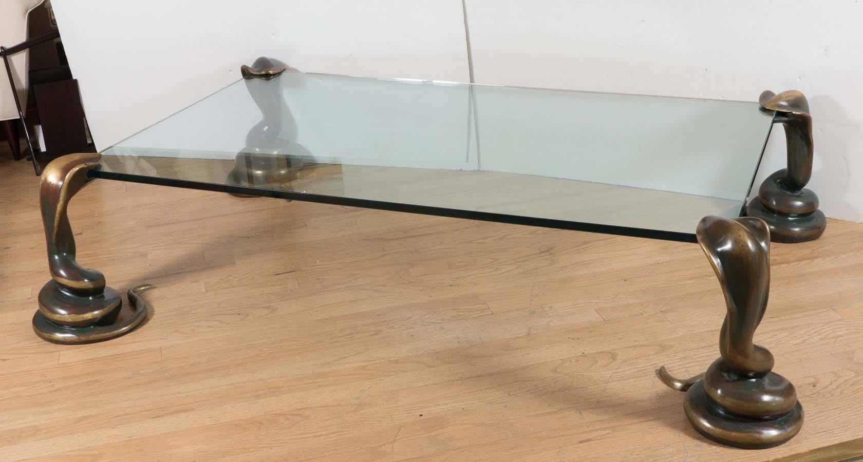 Rectangular glass coffee table with unusual bronze coiled cobra supports.