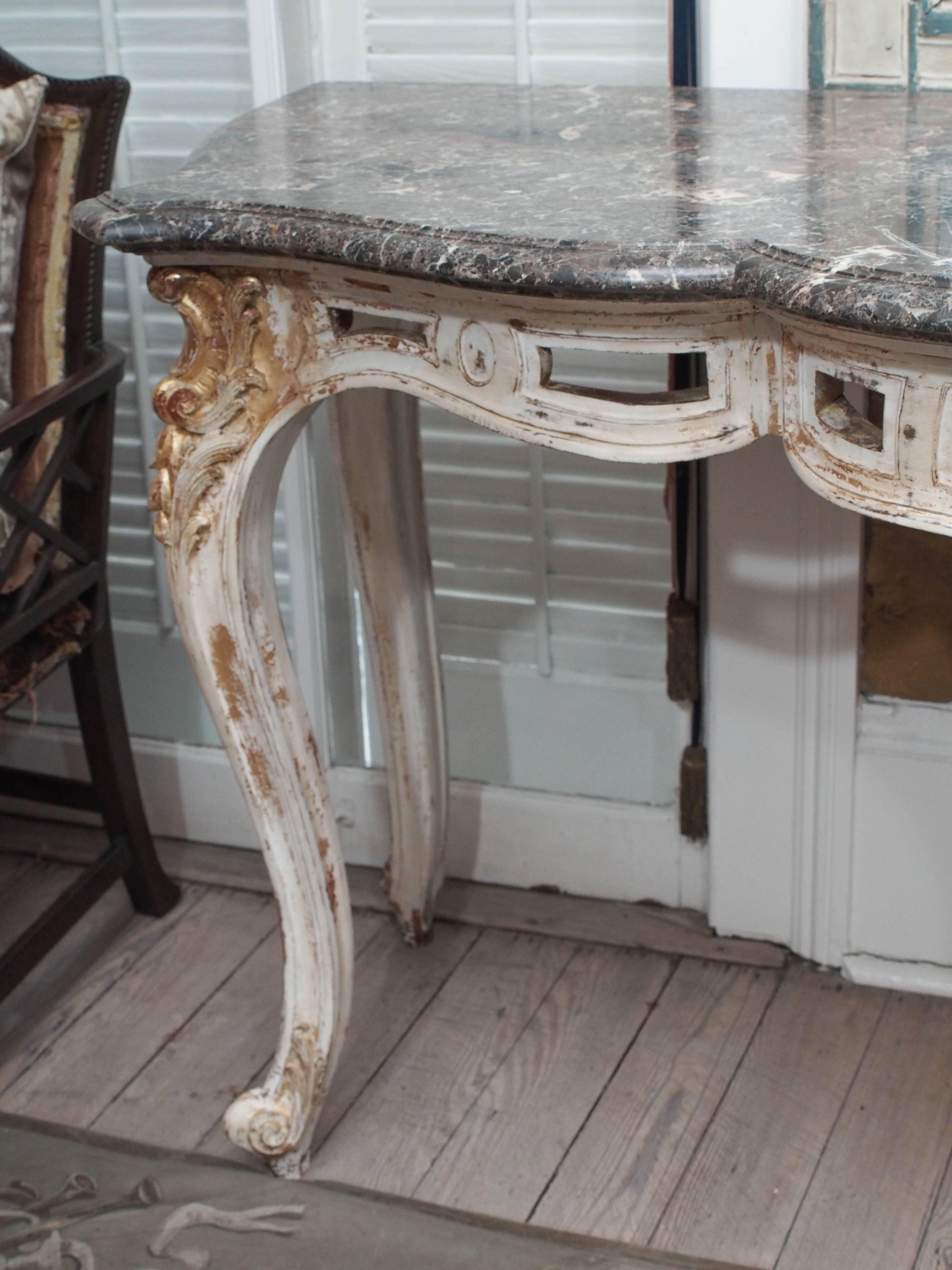 Regence style 18th century French console. Beautifully carved cabriole legs with whorl feet. Carved and painted front apron with a scallop shell design and carved trellis on the legs. Beveled black and white marble top.