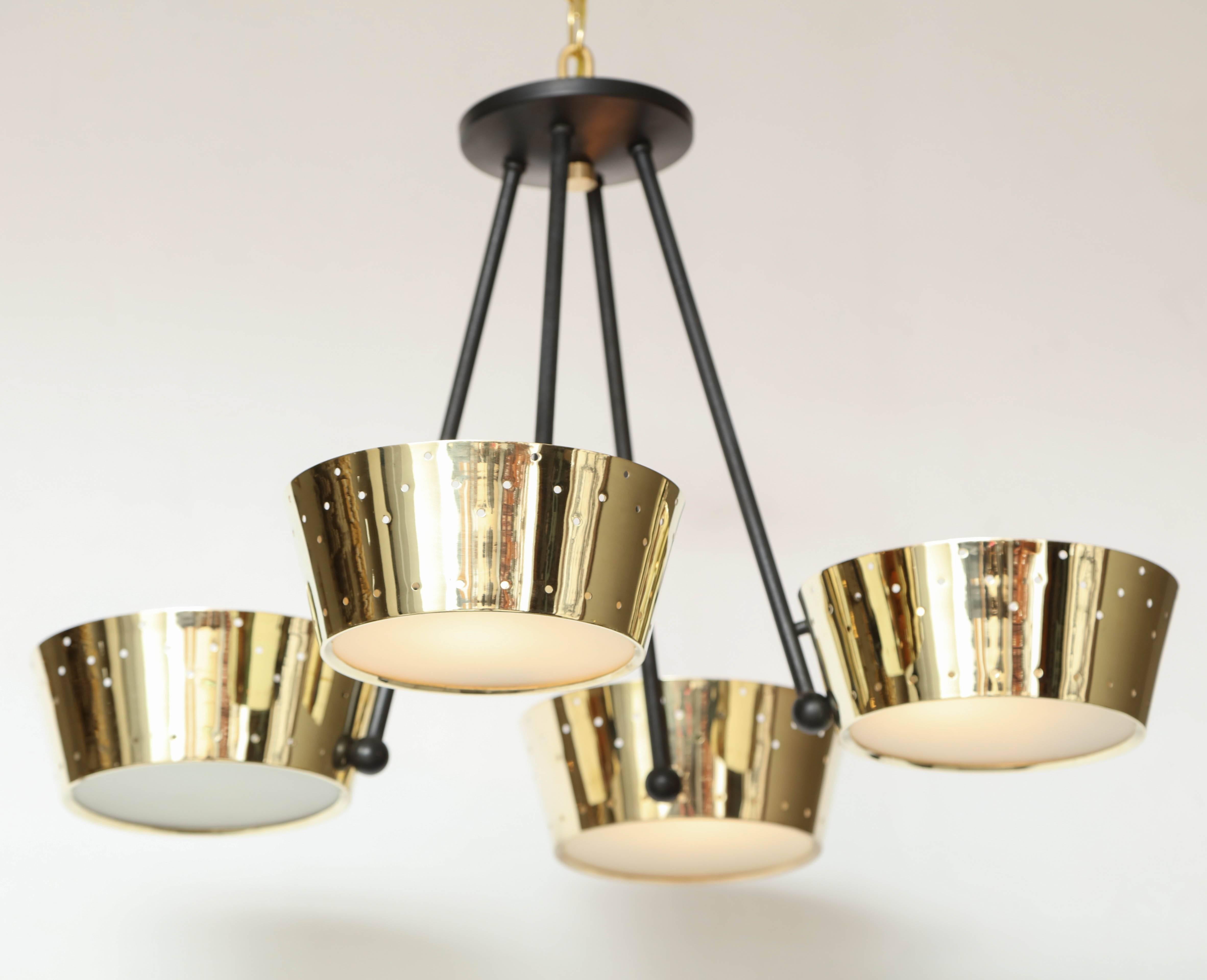 This mid-century modern chandelier by Gerald Thurston for Lightolier features four pierced brass cylinders with frosted glass inserts diffusing light at the bottom, joined by an black-painted steel frame. Newly restored, repolished and rewired.