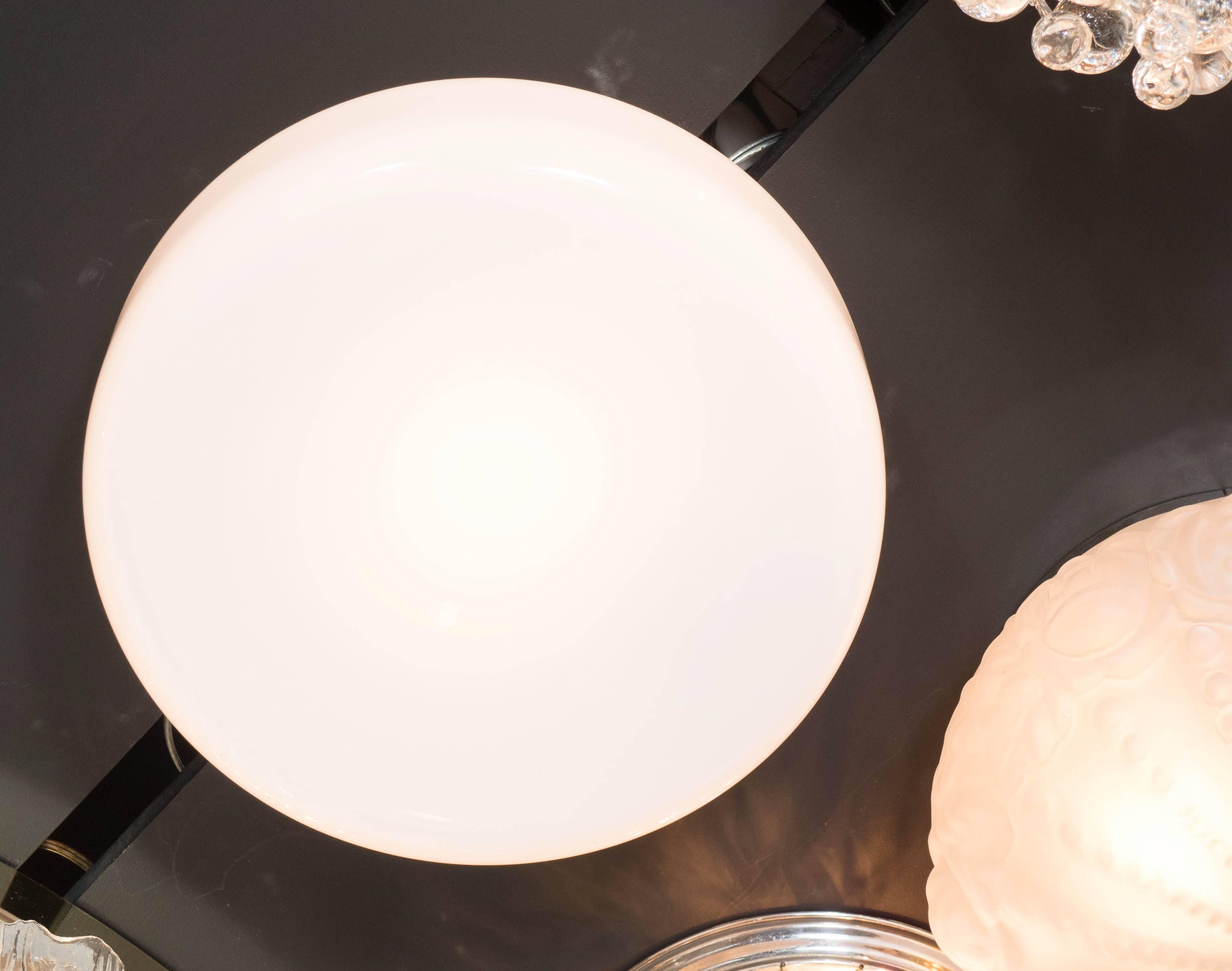 A Mid-Century Modernist flush mount chandelier featuring a seamless circular design in milk glass, when lit the entire chandelier emits a warm consistent glow. A great entry piece. It is newly rewired and in excellent condition.