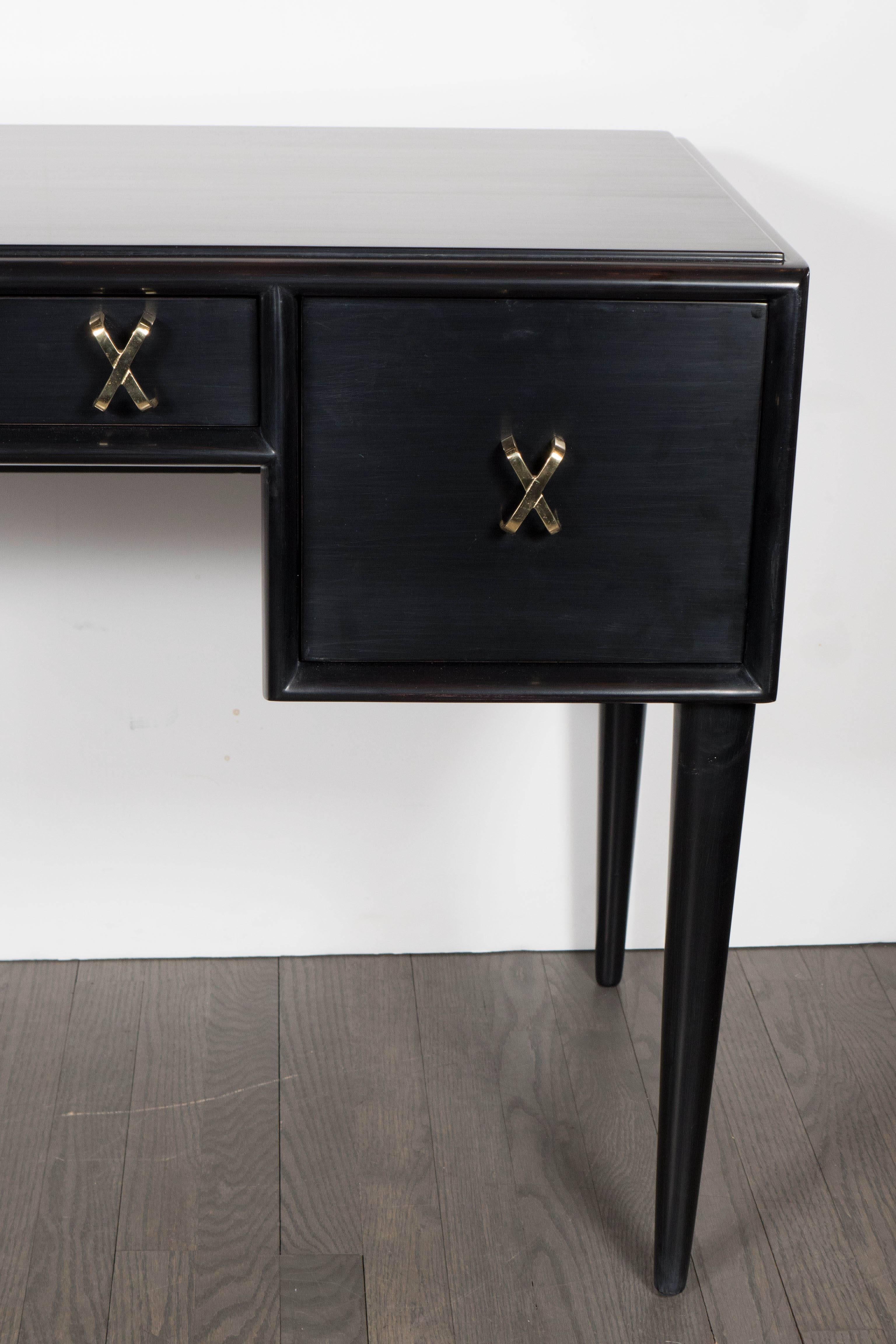 Chic Mid-Century Modernist desk or vanity in ebonized walnut by Paul Frankl for John Stuart Inc. Tapered legs support a three-drawer desk portion adorned with Frankl's signature brass 