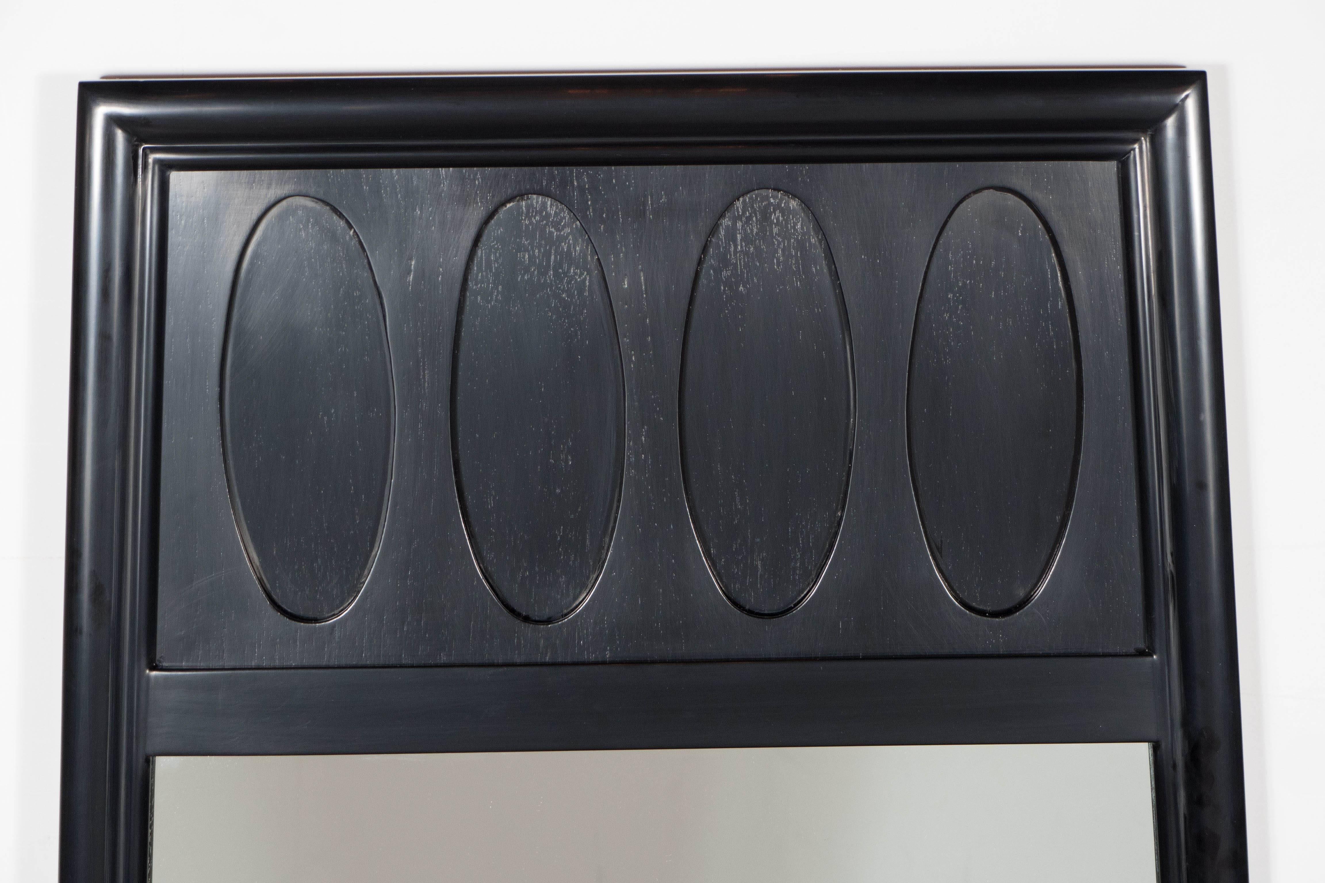 A sophisticated pair of Mid-Century Modernist mirrors in ebonized walnut. The frames are beveled while their top portions feature oval carvings. They have been restored to mint condition.

Price for a single: $2,975.