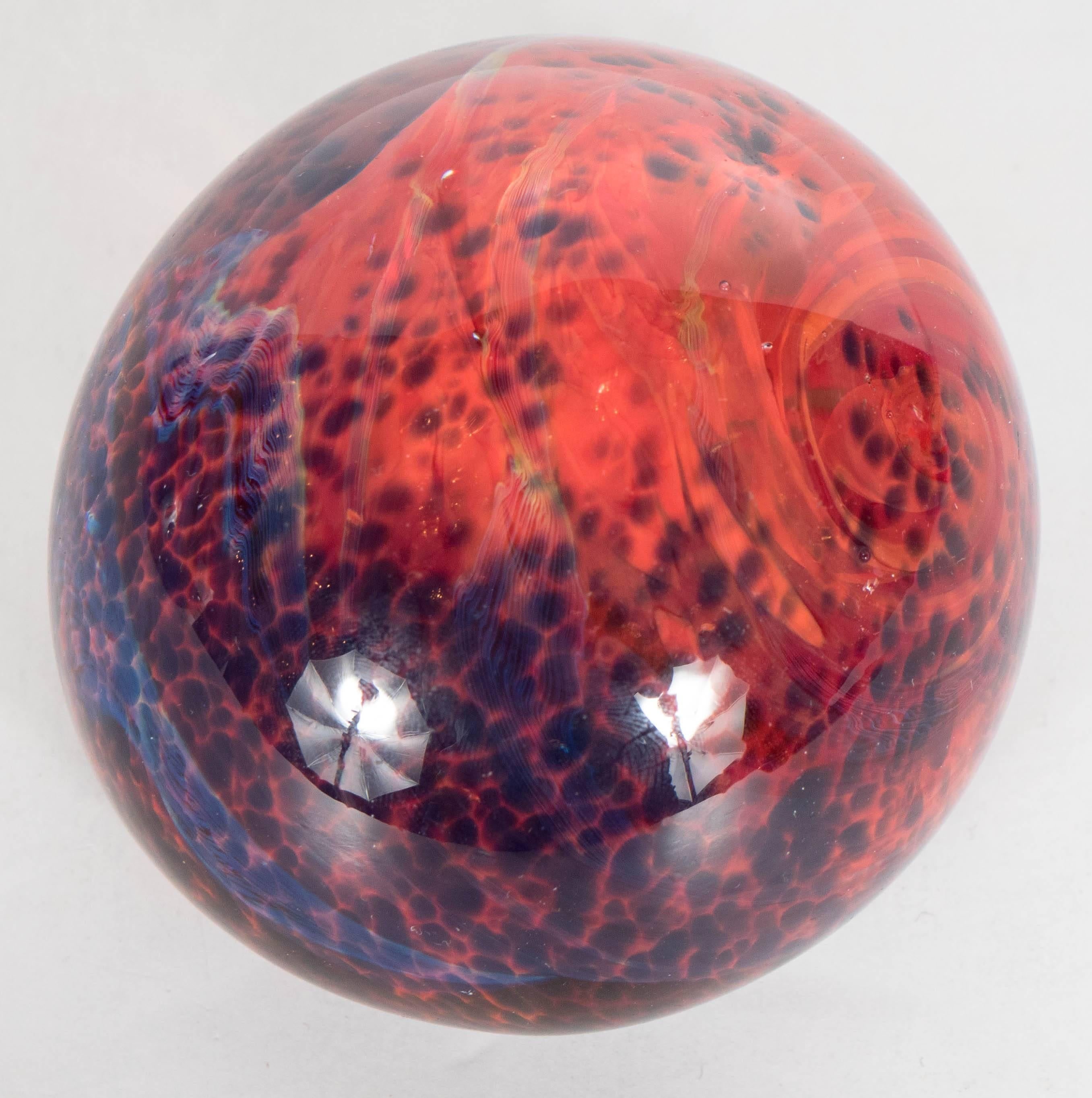 This gorgeous Mid-Century Modernist paperweight was blown by hand in Murano, Italy. It features constellations of cobalt blue specks and swirls of carnelian red suspended in translucent glass. This paperweight would be perfect for a desk at work as