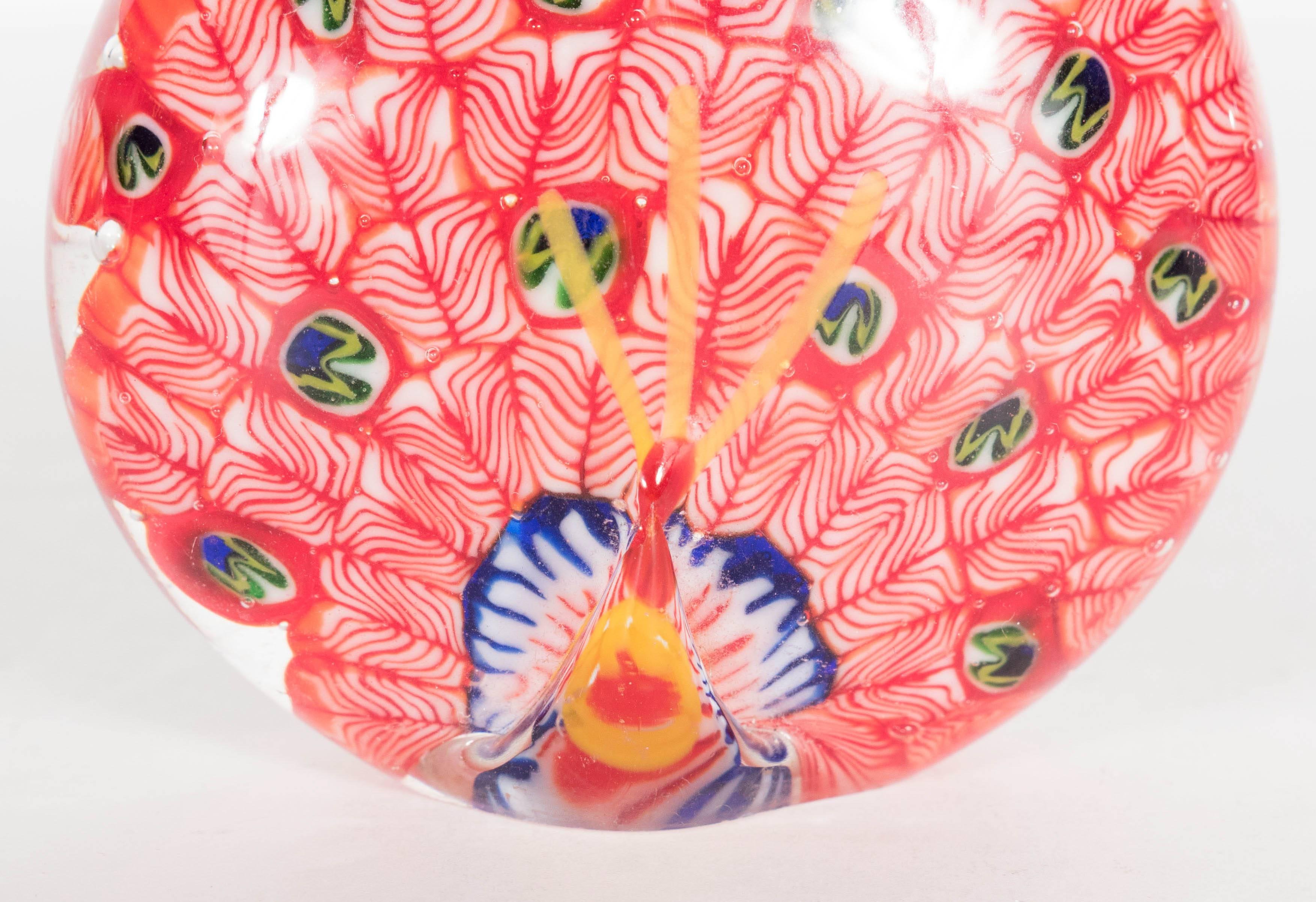 Mid-Century Modernist Murano peacock paperweight. Patterned red and white ribbon swirls adorn the piece, which are suspended in clear glass. This handblown piece of Italian art glass is in fine vintage condition.