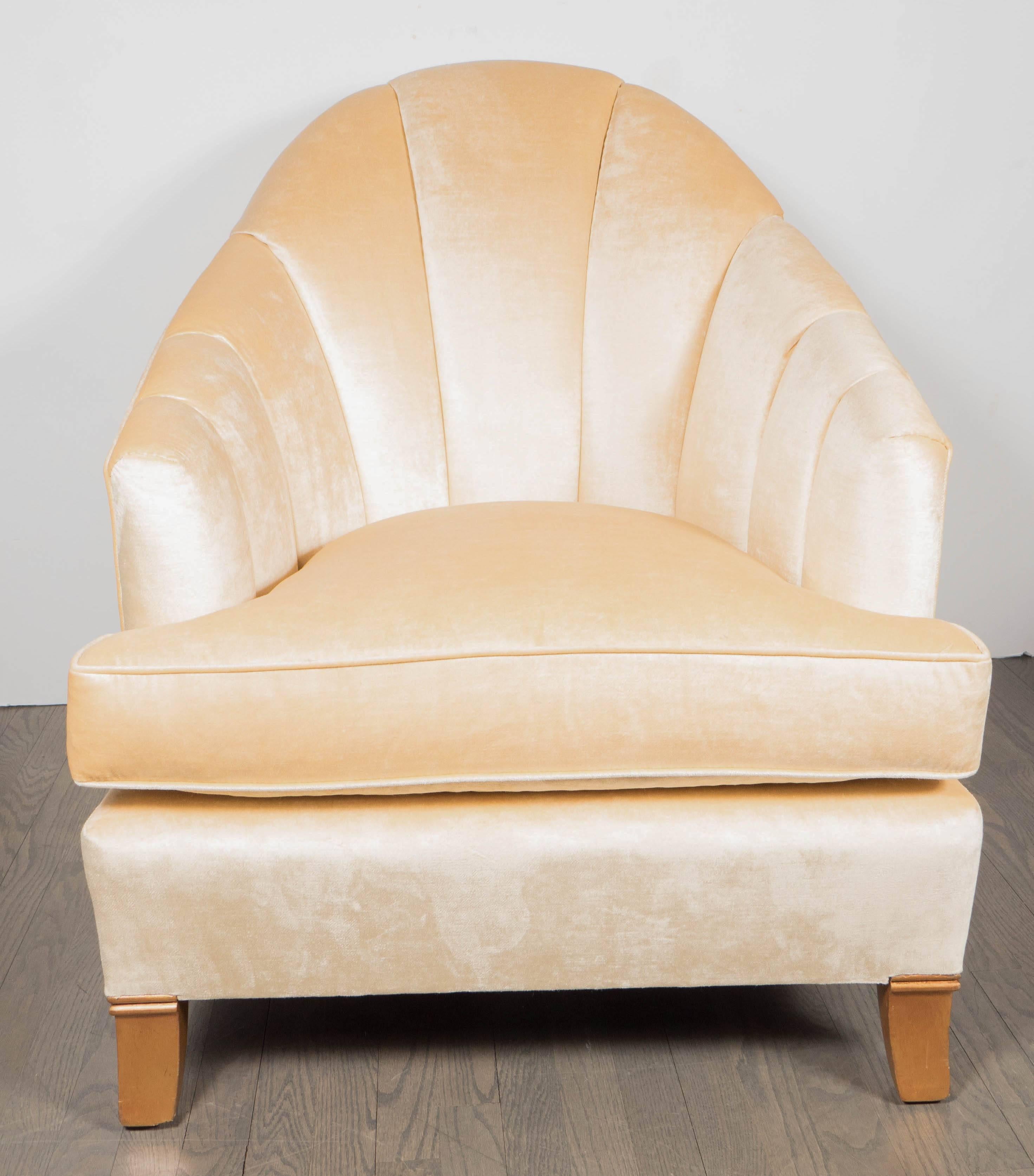 An elegant pair of French Art Deco club chairs with channel-back detailing. Newly upholstered in a cream oyster velvet fabric. Two rear-splayed and two front slightly-tapered walnut feet support each piece. A curved back and sloping arms make for a