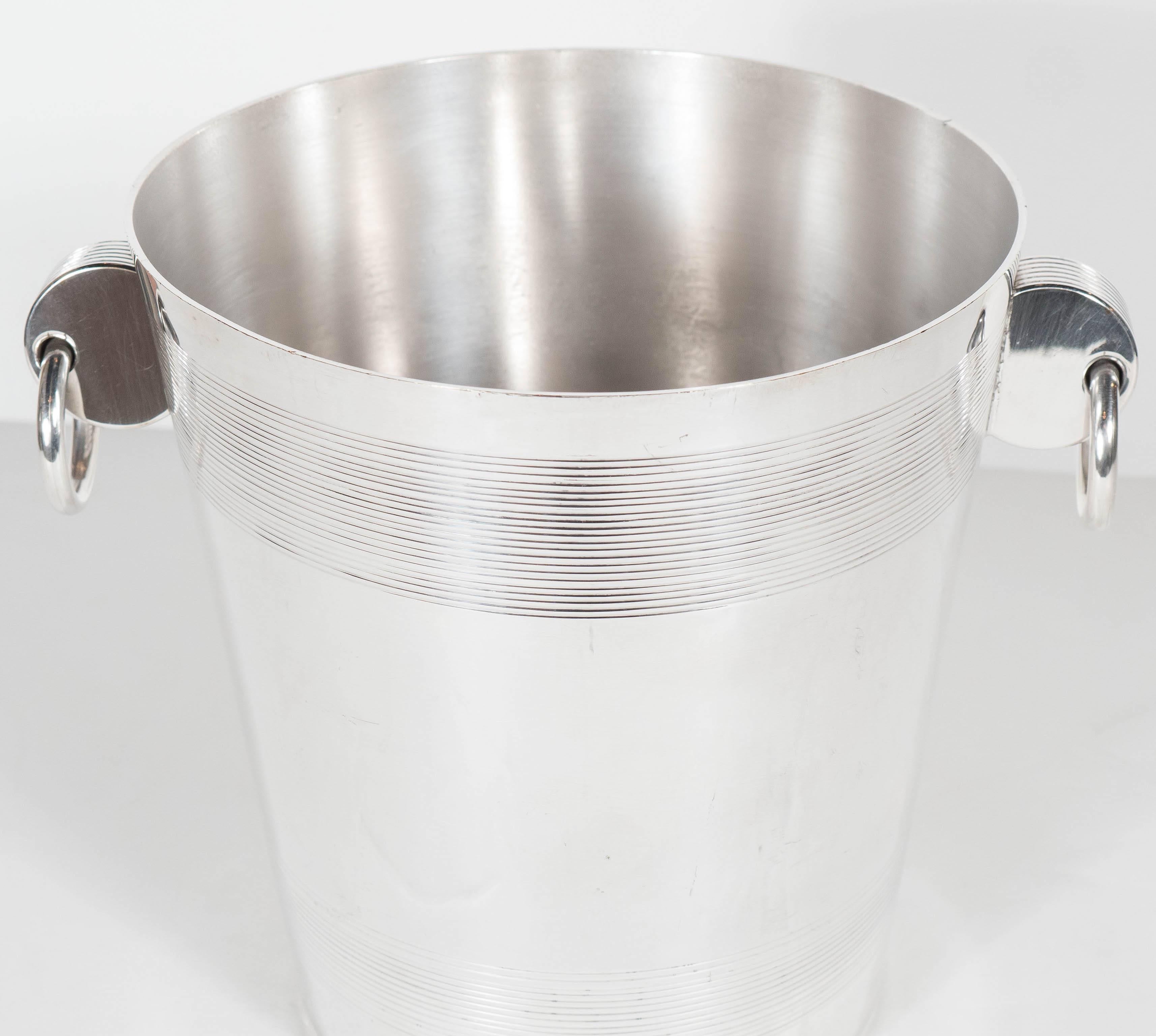 A handsome English Art Deco silver-plate ice bucket with stylized ring handles. A striped relief band is featured on the top and bottom parts of this piece. A perfect addition to any bar or cocktail service. This piece is in excellent condition.