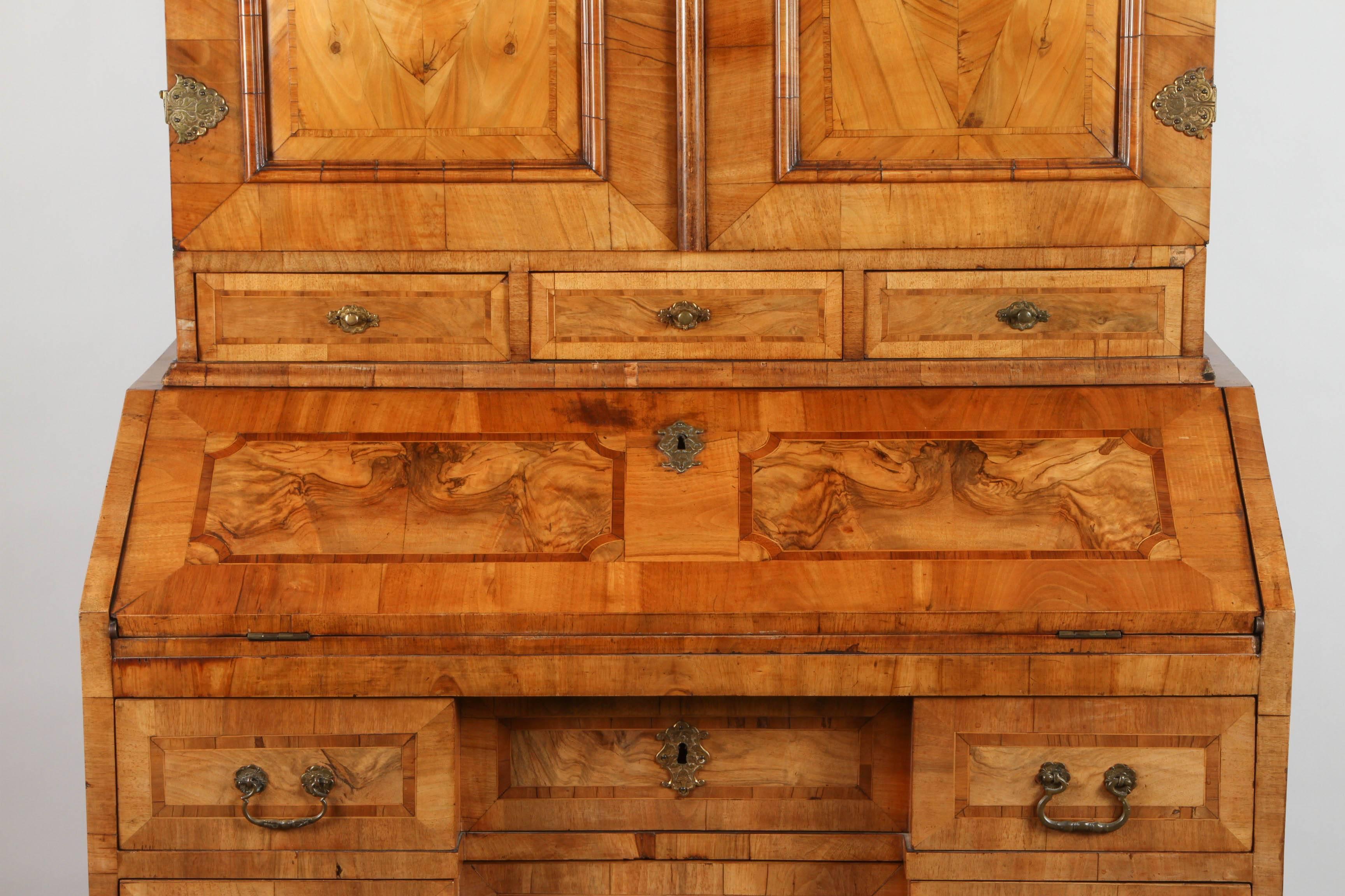 18th century walnut marquetry secretaire with brass hardware and overlaid hinges. The upper cabinet with two doors that open to reveal drawers and pockets. A later modification provides for two arms that swing out to hold a built in shelf. The lower