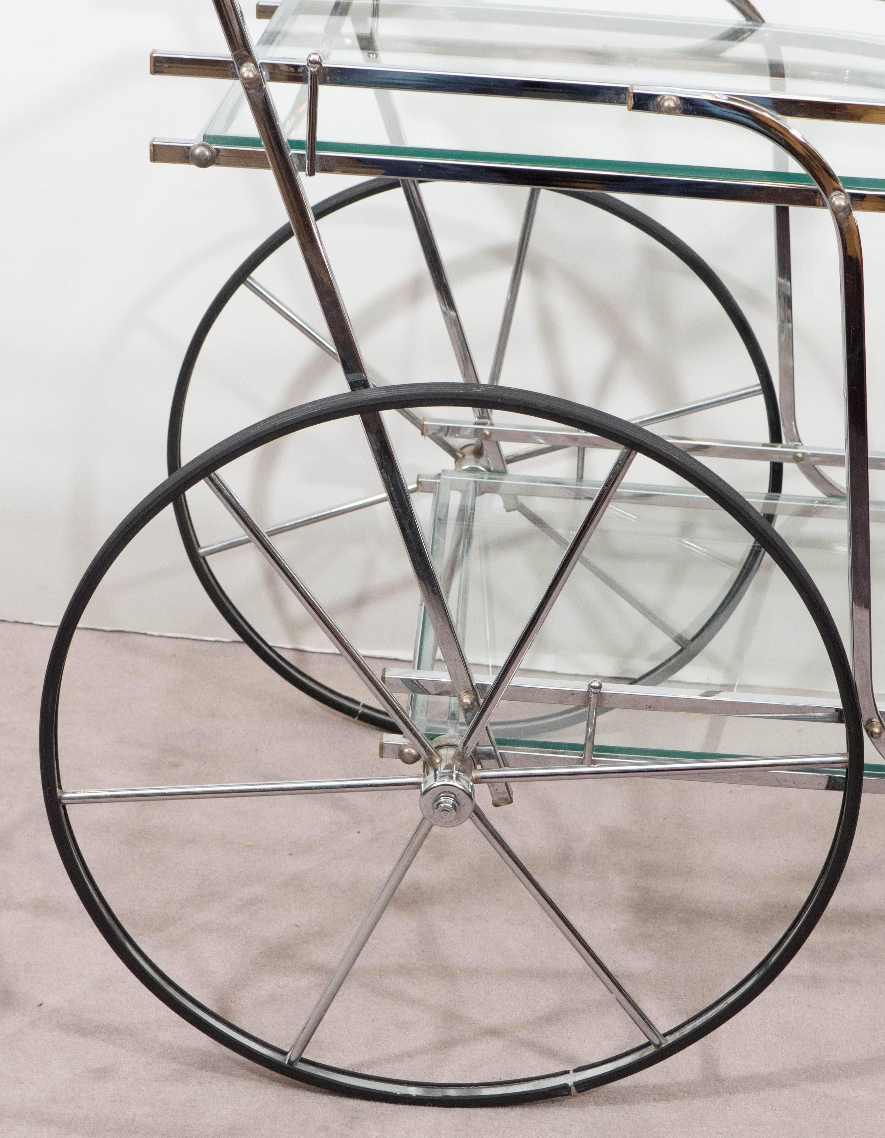 An exquisite two-tier bar cart in polished chrome, produced, circa 1960s with curved rope motif push handle, including glass tops with galleries, flanked by large spoke wheels and a front caster wheel. Very good condition, consistent with age; glass