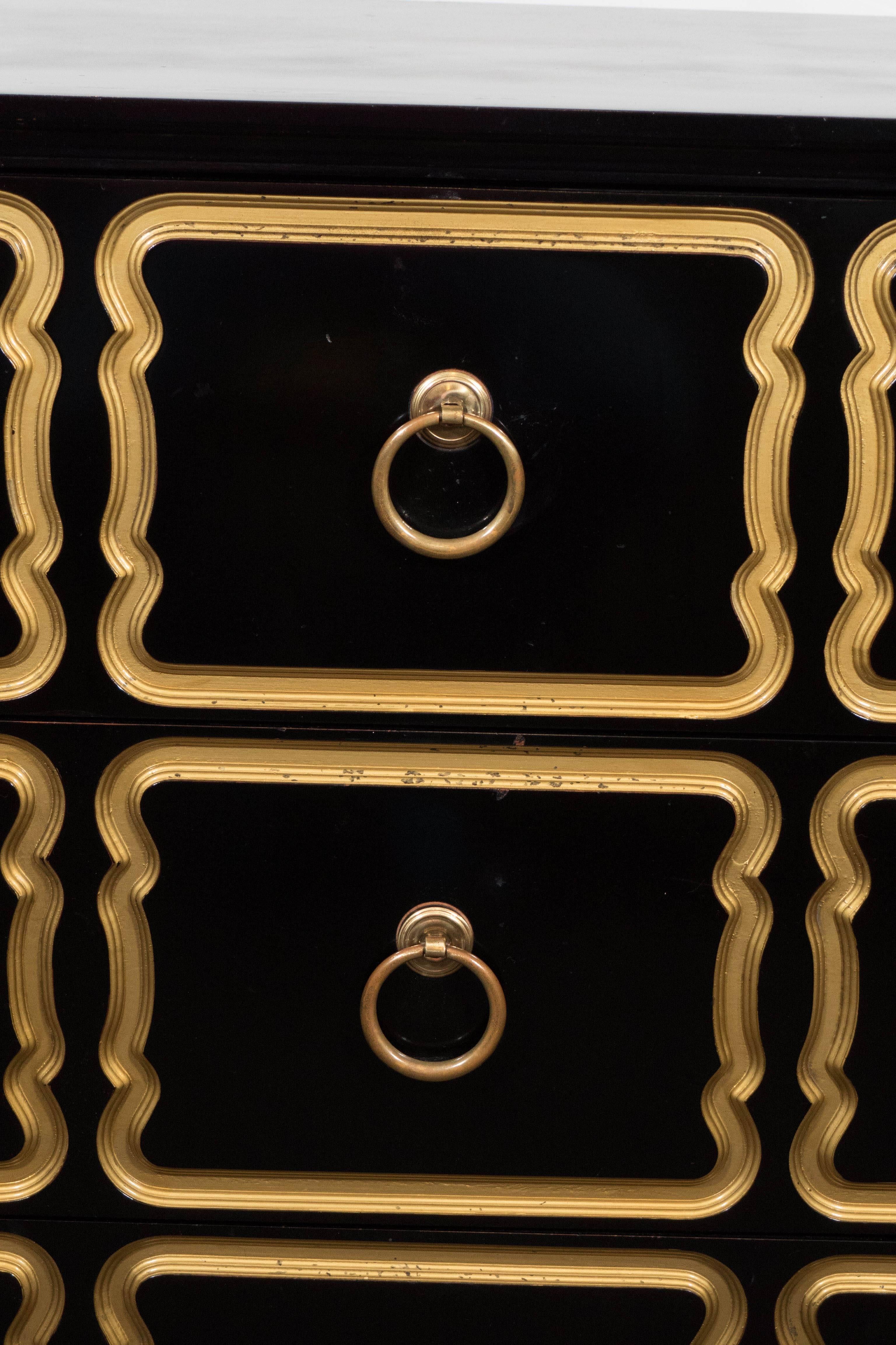 This pair of black lacquer Espana chests by designer Dorothy Draper, circa 1950s, includes three drawers with three brass ring handles, each bordered by beveled gilt trim. The chests remain in overall good vintage condition, with age appropriate