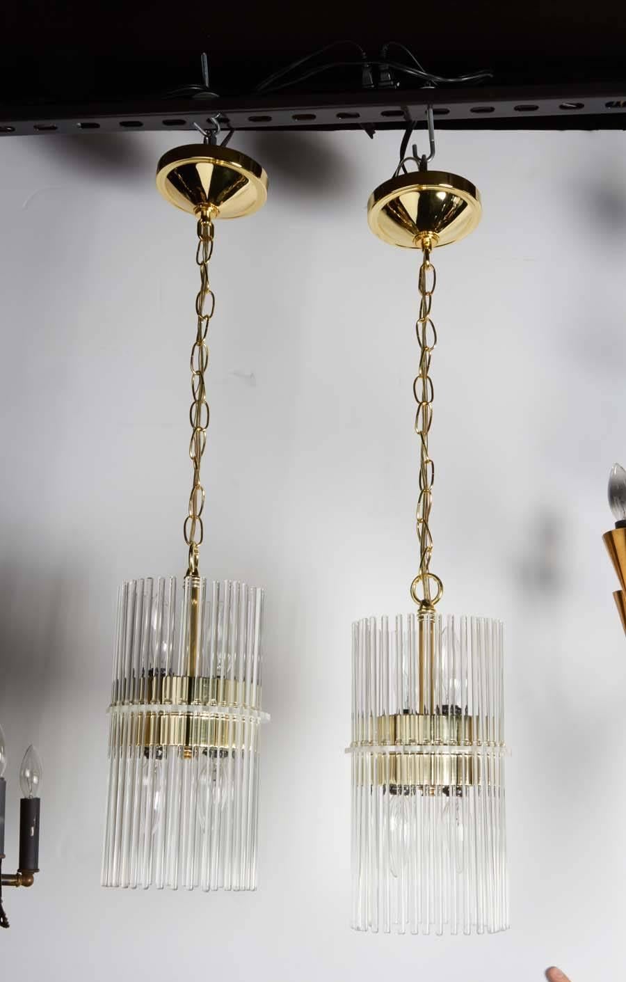 Pair of modernist glass rod pendant lights by Gaetano Sciolari for Lightolier. The fixtures have a lantern style design featuring numerous glass rods that independently suspend from a Lucite center disc. The pendants have a brass inner frame as well