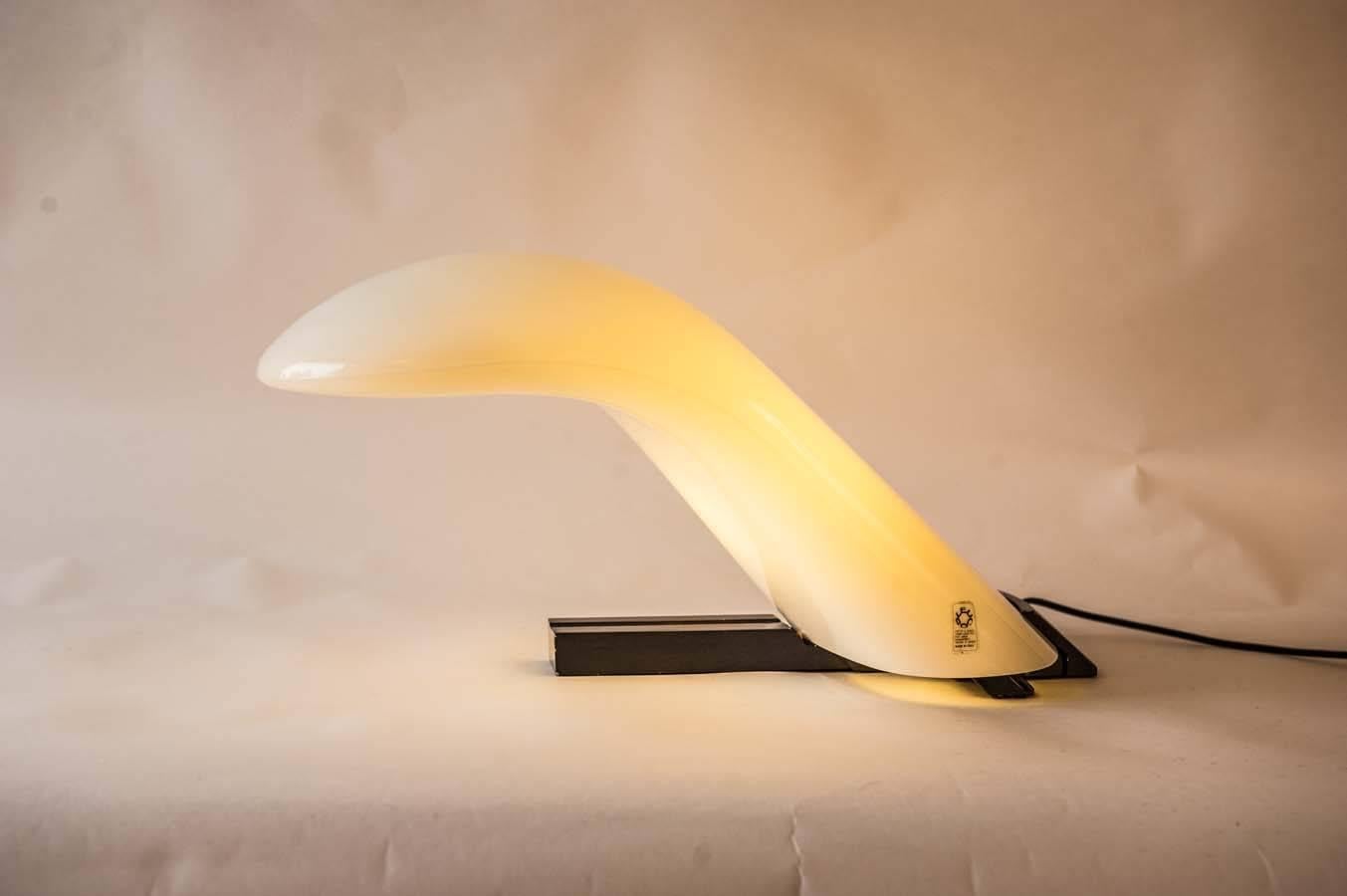 Wonderful arch shaped table or desk lamp by Italian light specialist Leucos. Its base is made of black colored steel. The light bulb itself is placed in an aerodynamically shaped Murano glass object that seems to finely seems to balance on its black