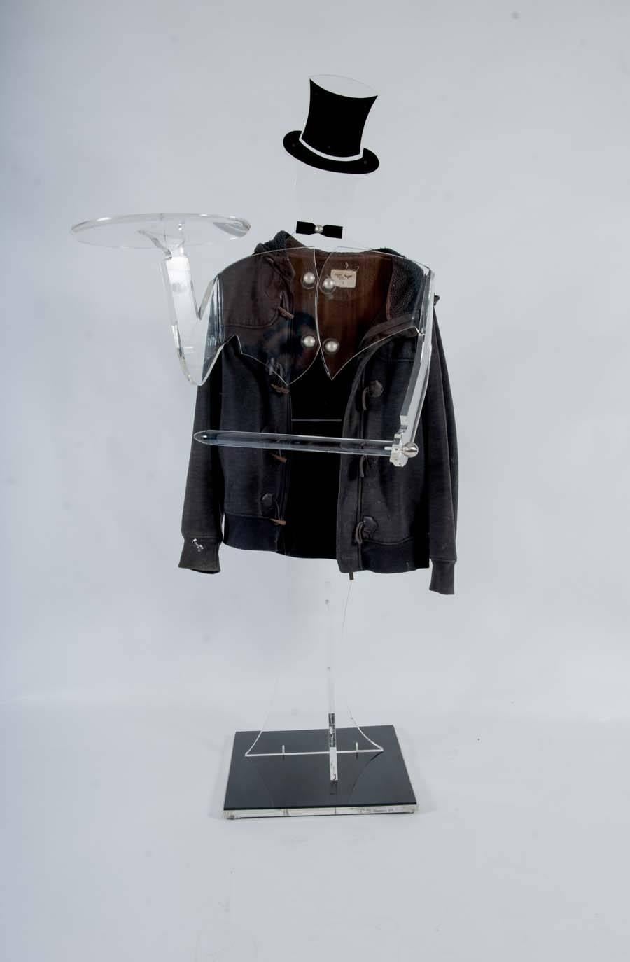 Stylish Present Boy or Waiter, which can also be used as a Dressboy. 
This almost man-sized figure is entirely made of plexiglass, including the detachable arms. 
Base, hat and bow tie are black; the rest is transparent. 
The four buttons of his