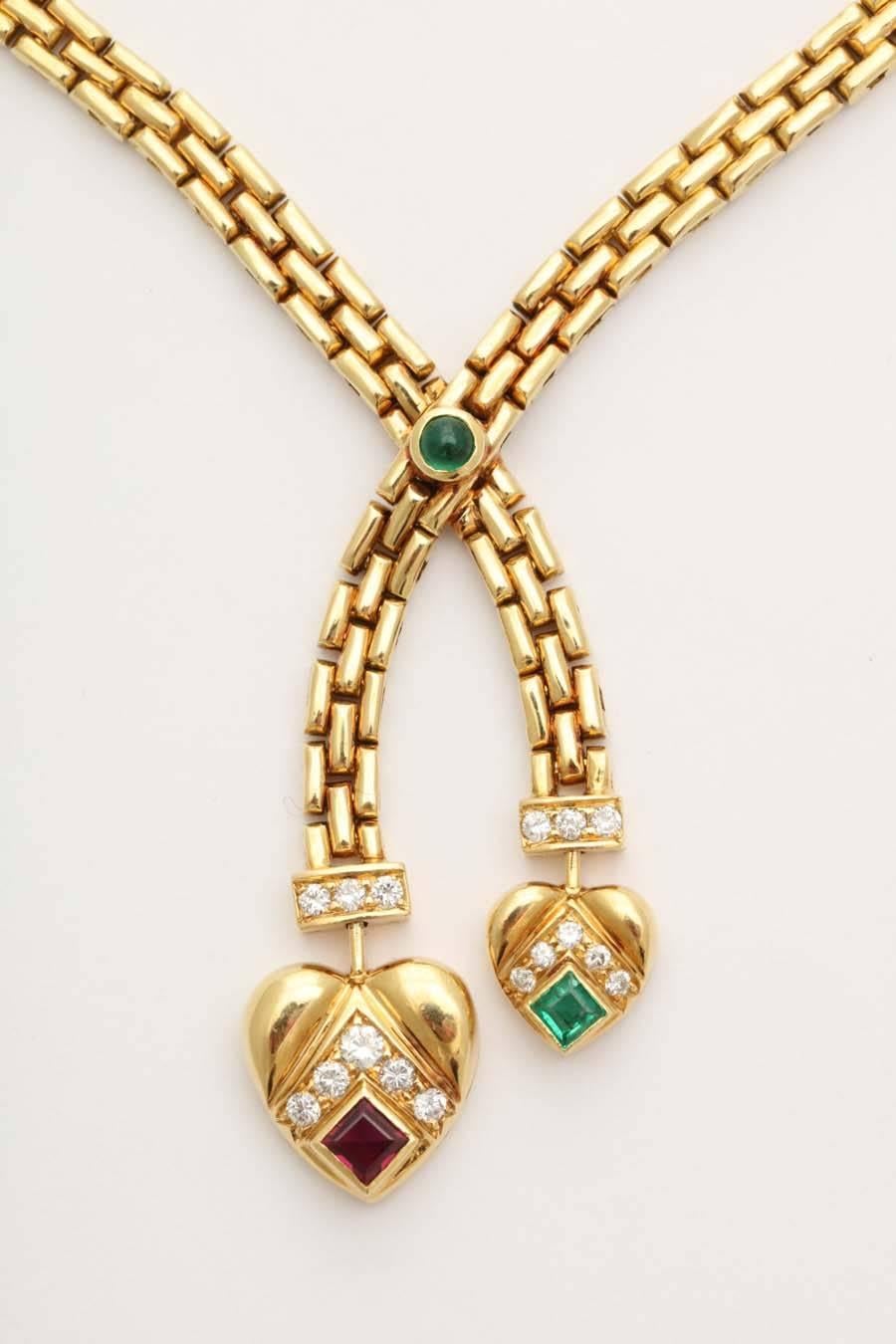 A Classic stylized beautifully articulated 18-karat gold necklace of flat Greek key design with asymmetrical hearts with a combination of small square diamonds, square ruby and a square emerald with a cabochon emerald accent. The necklace is signed