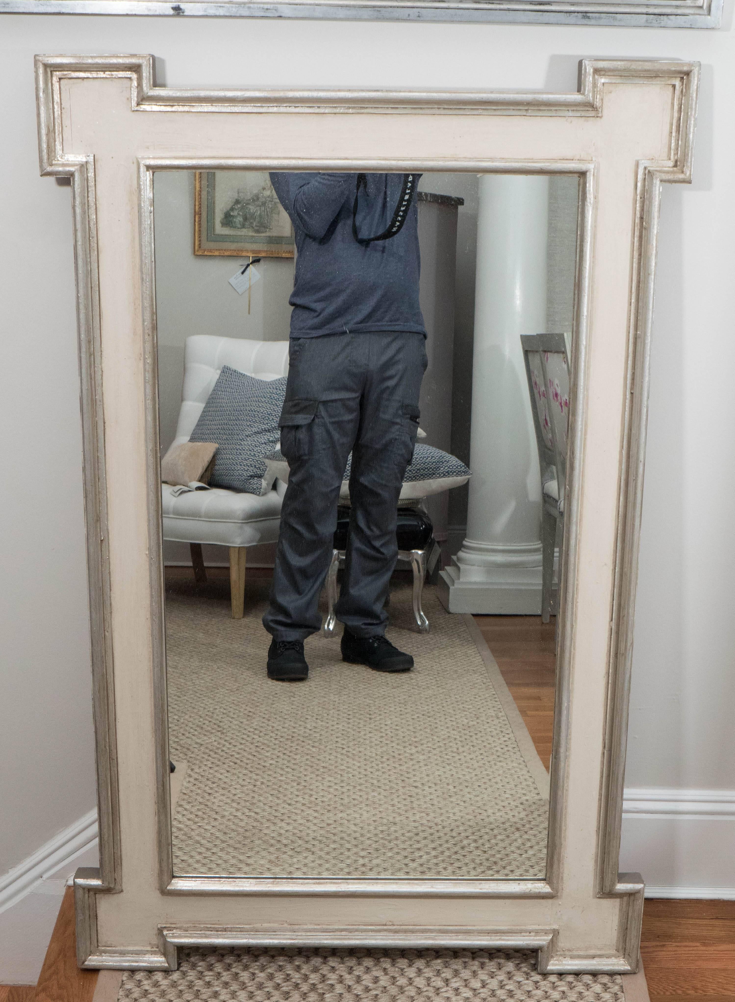 A mirror in a grayish white finish with silvered trim and inset corners, made from reclaimed wood.