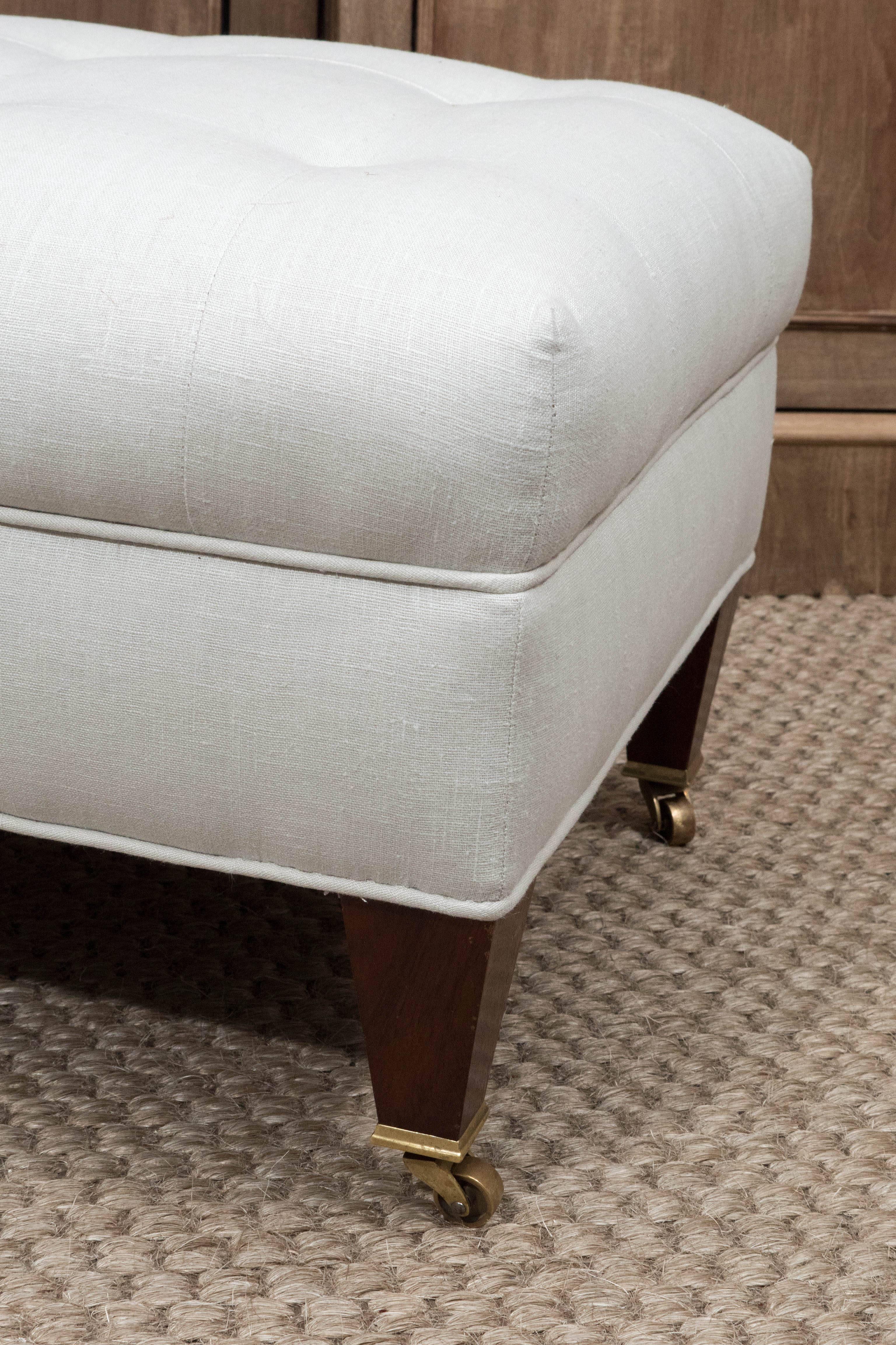 A sleek, tailored ottoman with button tufting on tapered legs with casters. The clean lines and size of this piece make it very versatile it can be used in a bedroom, office, tv room or living room. It has been newly re-upholstered in a soft gray