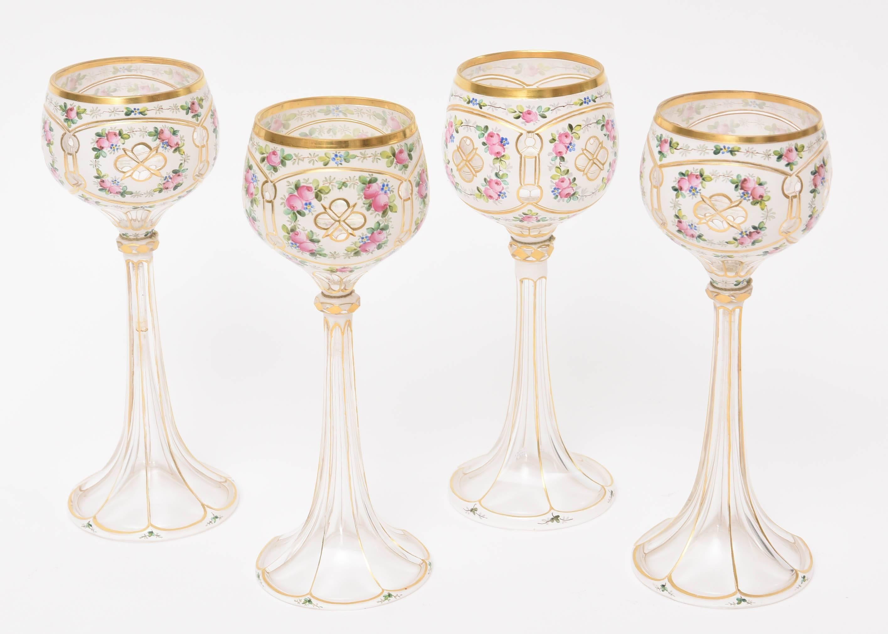 A set of four stunning wine goblets featuring a beautiful white cased glass over the clear with a blown scalloped trumpet shaped stem. Hand-painted florals and 24-karat are lavishly applied to each one. These are nicely proportioned and feature a