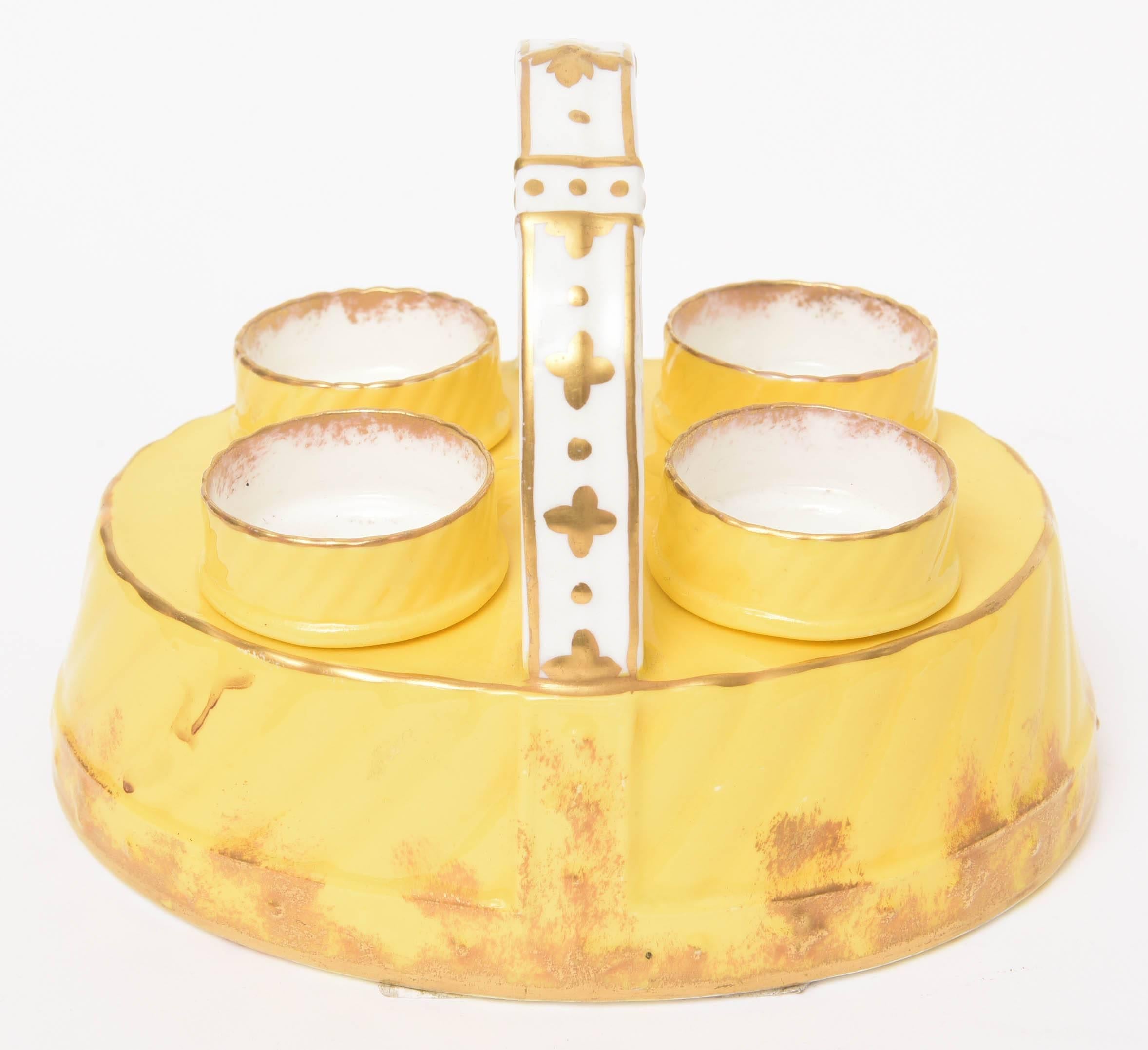 A charming and delightful set just in time for Spring. Very fine English bone china by Hammersely and Co with a rich and vibrant yellow color and hand decorated gold design. 4 egg cups nestled in a handled basket form. 
The overall holder measures