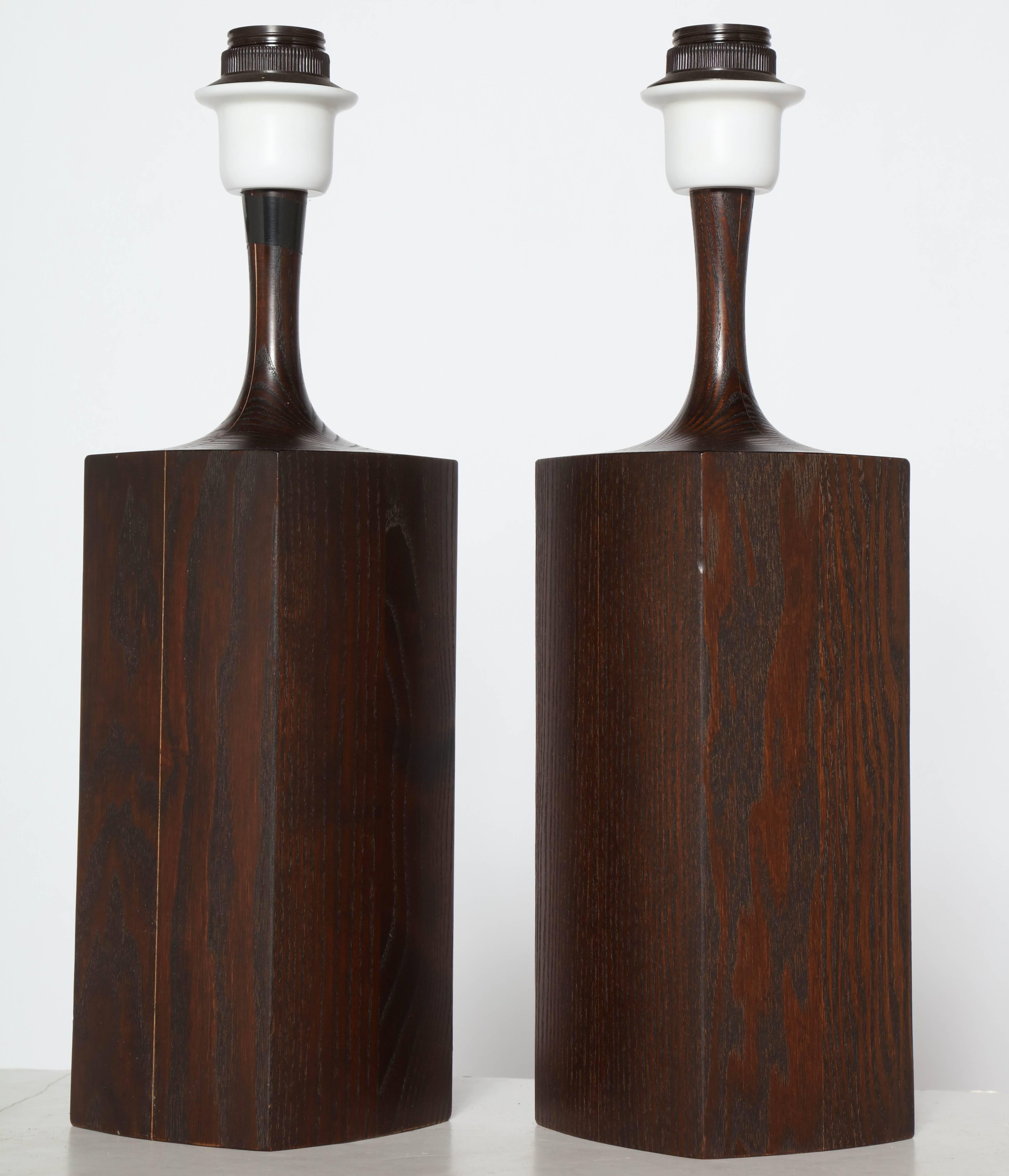 Pair of Scandinavian Modern Dark Solid Oak Table Lamps with Deep Brown finish. Featuring a rectangularly constructed, biomorphic bottle form with Jacobean finished Dark Oak and highlighted by White molded plastic cap detail. Beautifully grained.