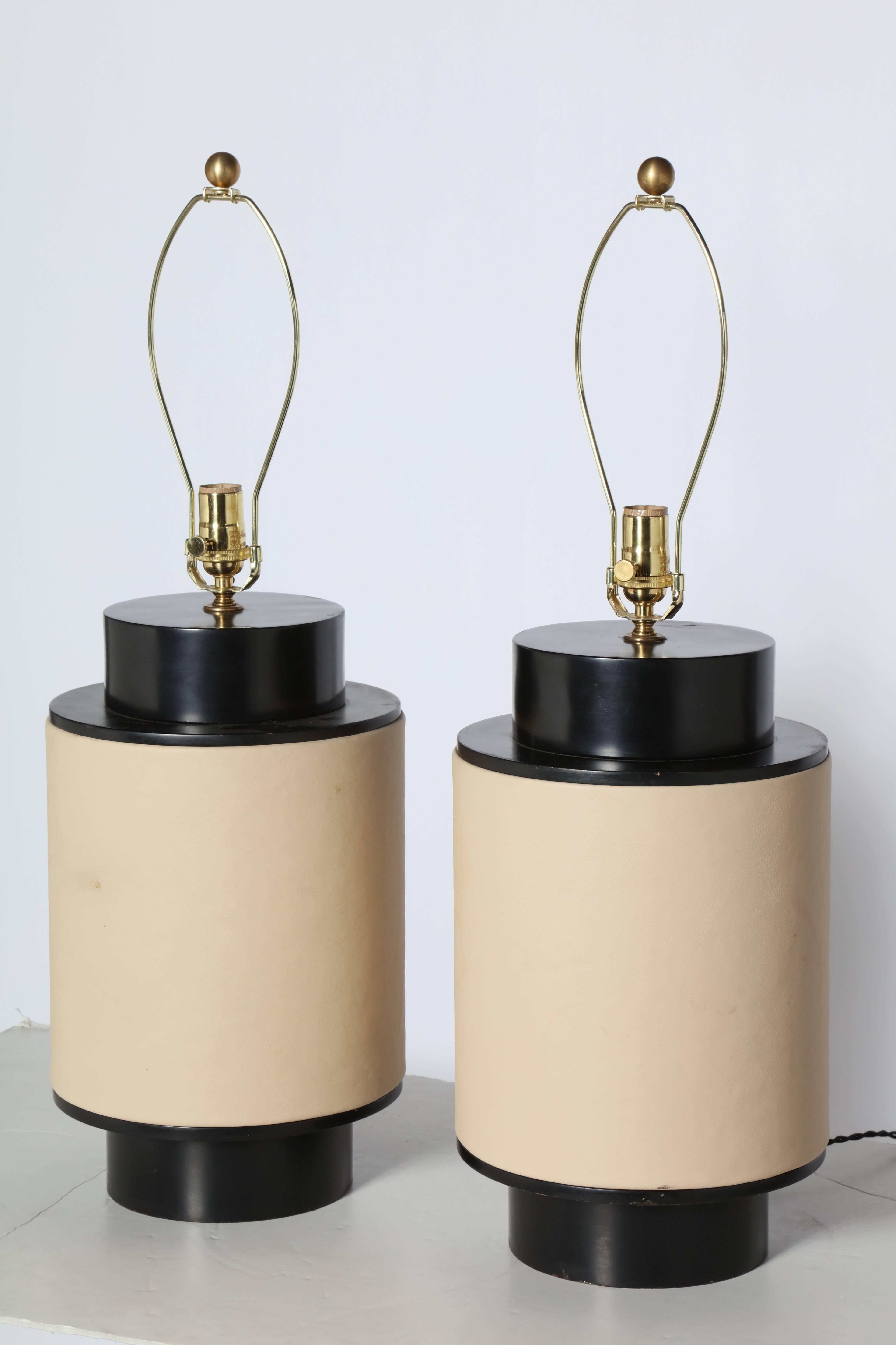 Large Pair of Tan Wrapped Leather and Black Barrel Table Lamps, Circa 1950. Featuring wide, set back, ebonized Black enameled Wood Barrel forms, center wrapped in taut Beige Leather. Top of Finial: 29.5H. Top Black Enamel: 16.75H. Top of Barrel: