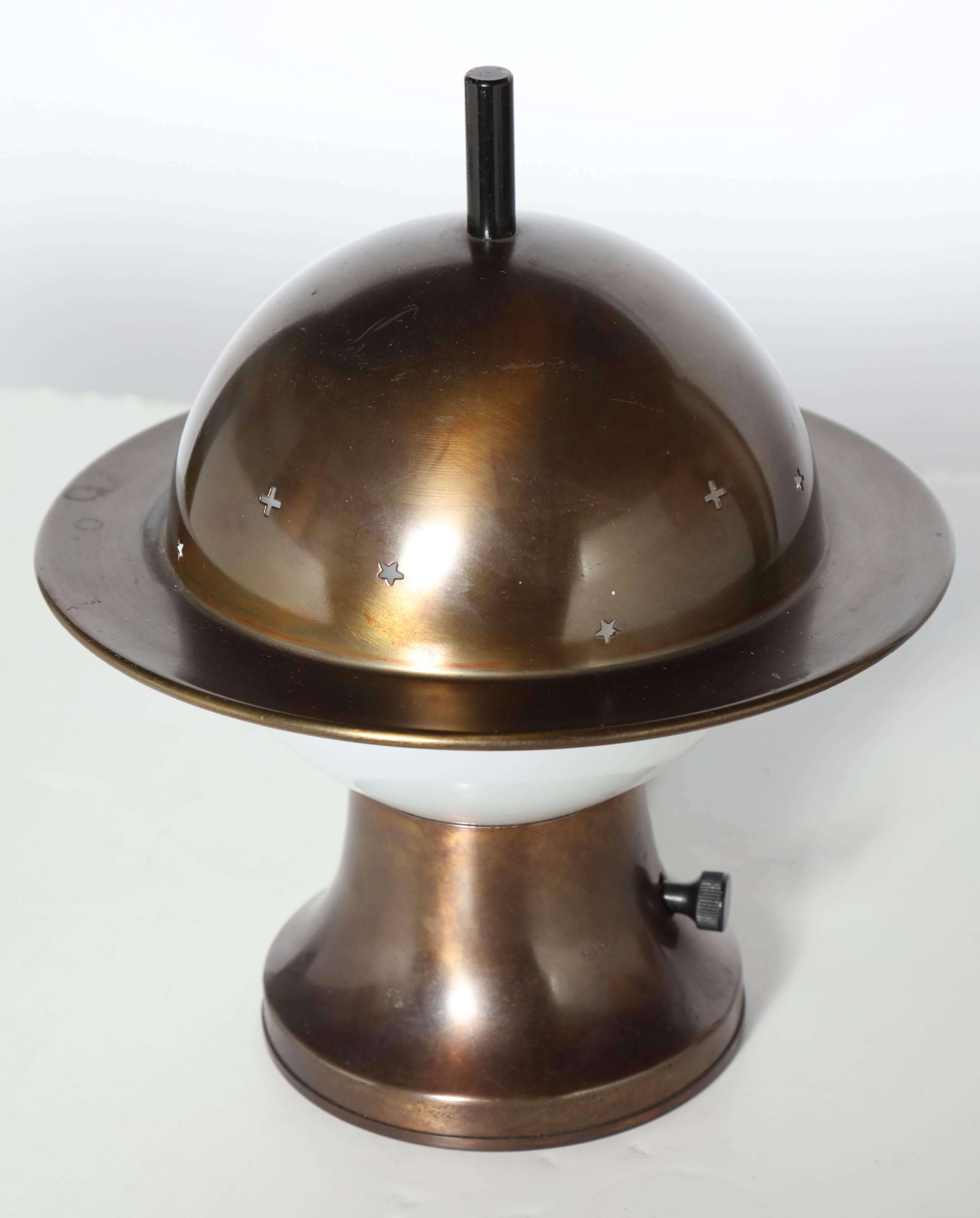 Circa 1935 Walter Von Nessen for Chase Brass and Copper Company Constellation Brass Table Lamp. English Bronze finish. Pierced Brass helmet Shade with constellations. Round Opaque White Milk glass shade. Flared Brass base. Saturn. Heavenly.
