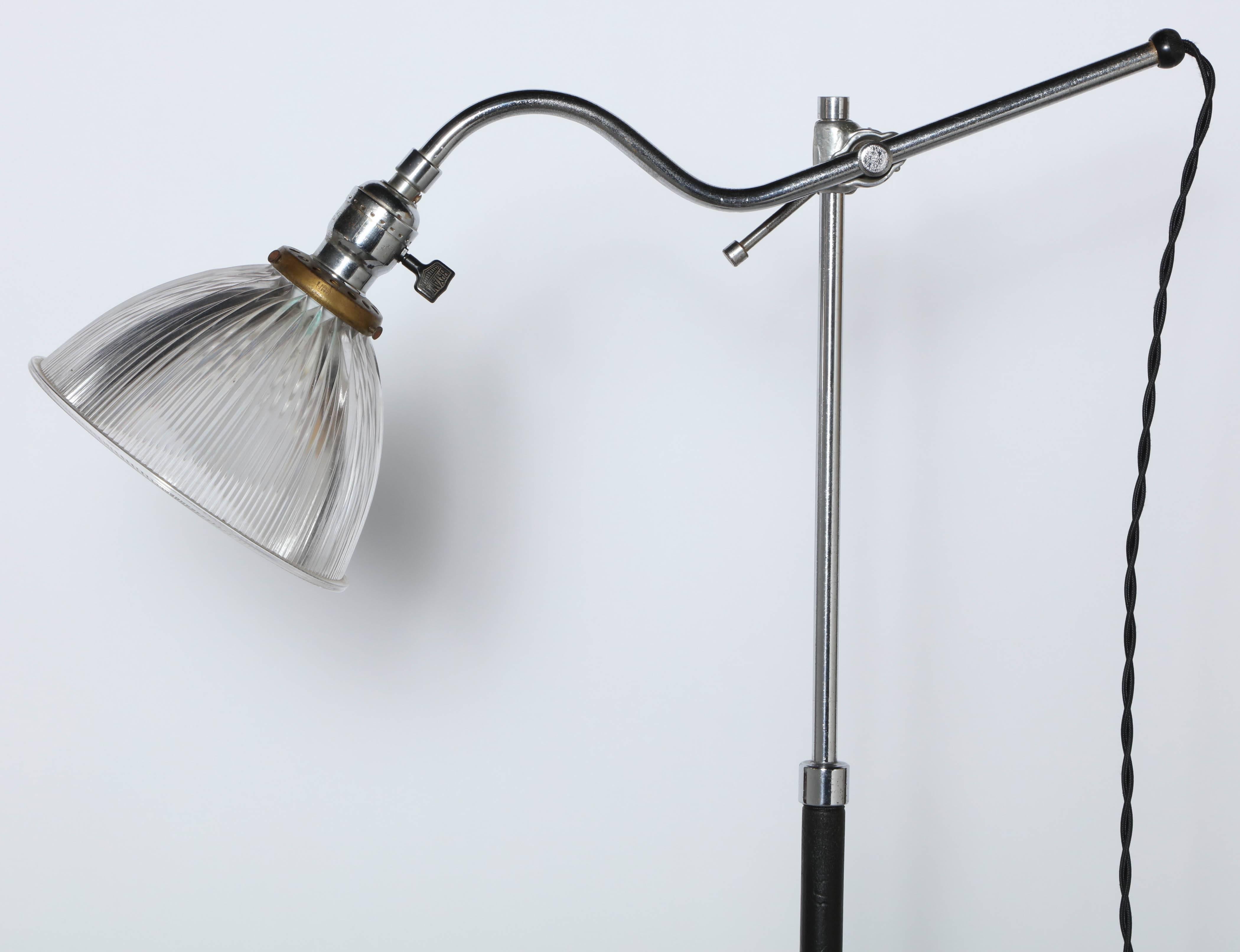 Early 20th century steel, chrome plate, cast iron and black column floor lamp with clear holophane glass shade. Featuring an articulating chromed steel arm, adjustable chromed steel and black enameled metal column, ribbed transparent holophane glass