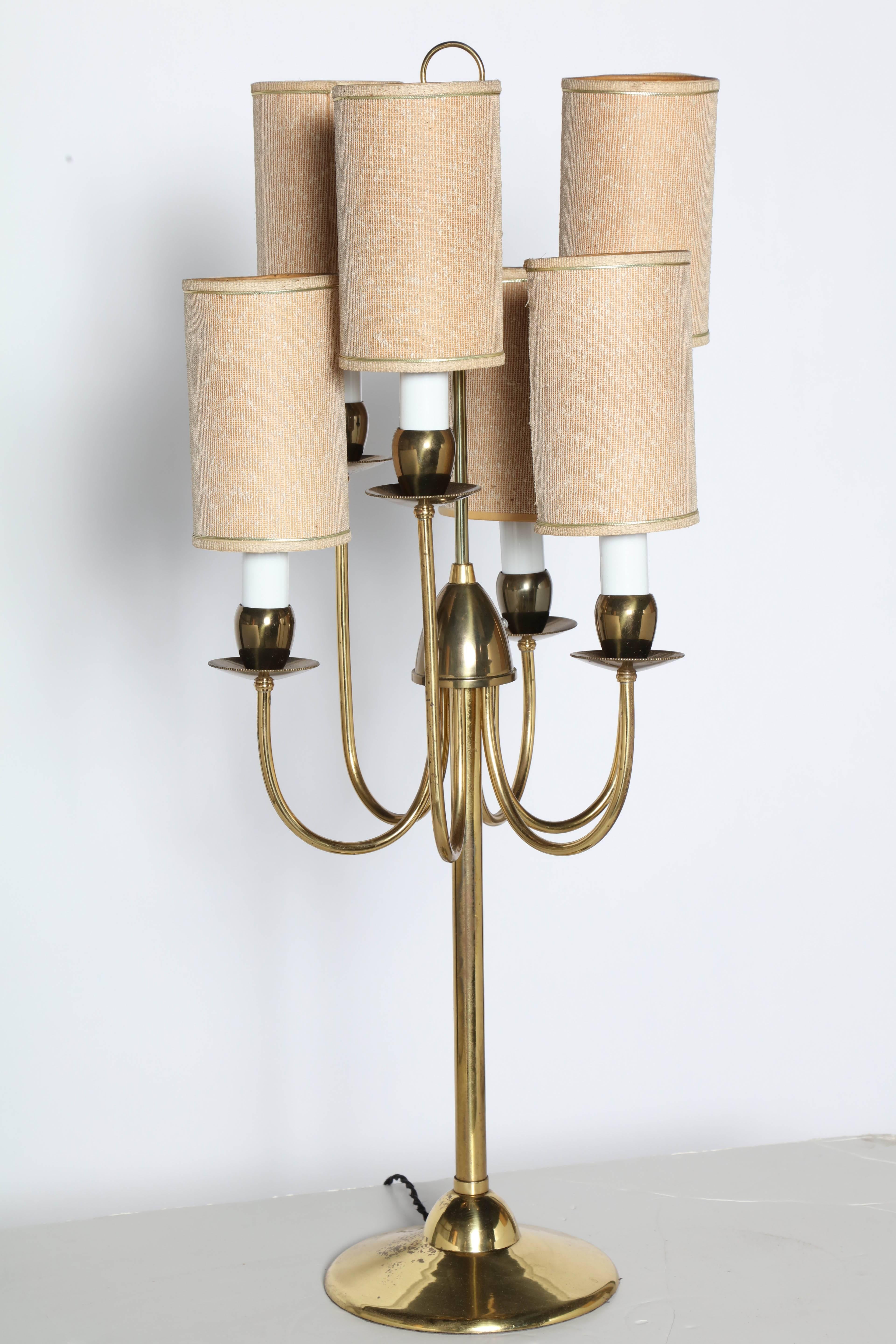 Majestic Two Tier Brass Six Candlestick Table Lamp in the manner of Tommi Parzinger, Circa 1960. Featuring six curved Brass arms, six Off-White candlesticks, six original cylindrical, woven fabric over paper, clip on Oatmeal Shades on a round