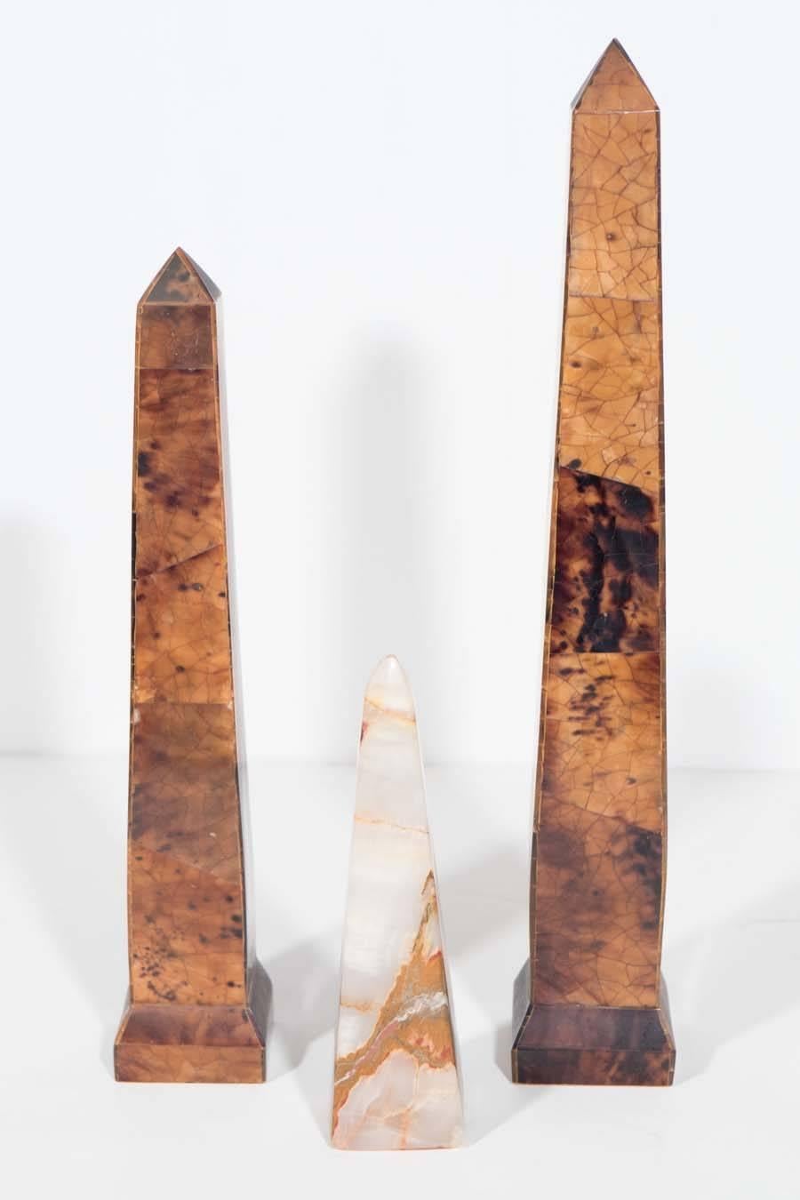 This set of three obelisks feature a tortoise color shell overlay on two of the pieces and the other in a rich solid carved onyx in natural hues. They are great as an interesting grouping for a table, cocktail table bookcase or etagere.