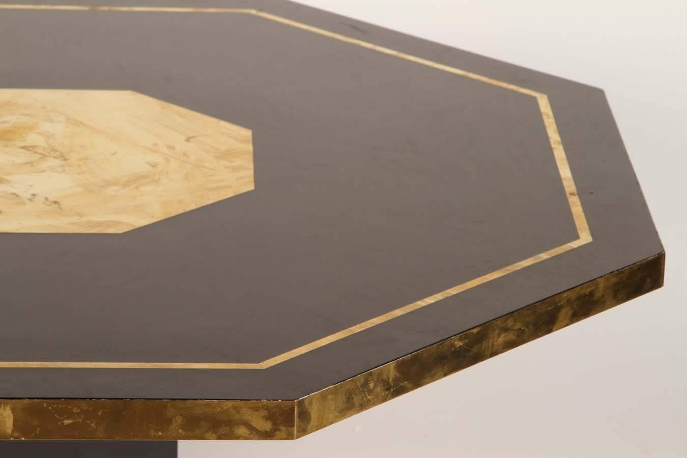 This wonderful black lacquered octagonal table, has glamorous brass accents including an inset panel. It is a wonderful example of Mahey's early work, exemplified by the noble materials used with exuberance. 
This table could be used as a game