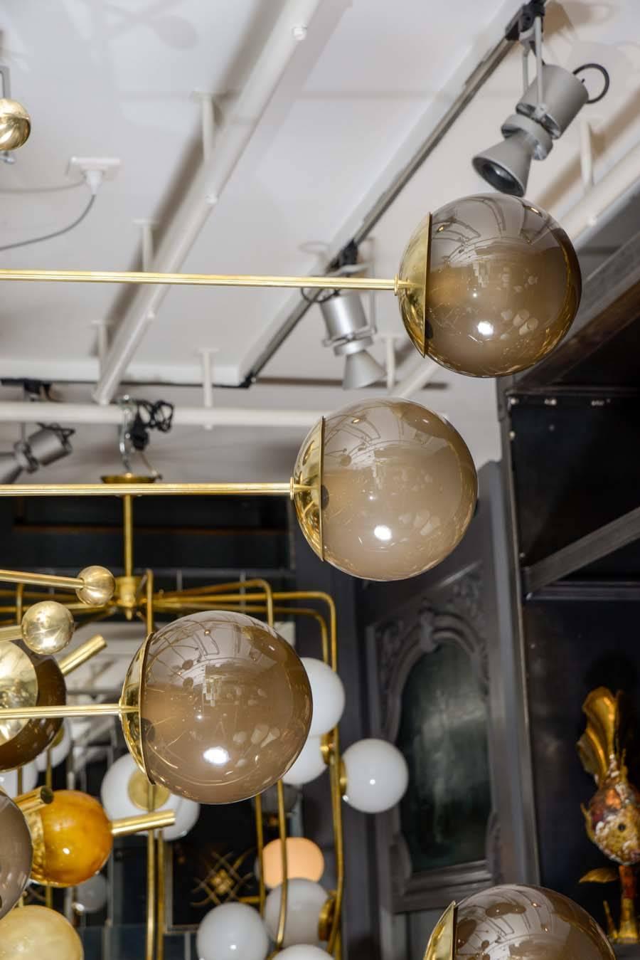 Vertical chandelier made of a brass body from where start 20 arms of light of different lengths giving the illusion of a spiral.
Each of the arms ends with a large Murano glass brown globe.
Between the arms you can find decorative stems ending in