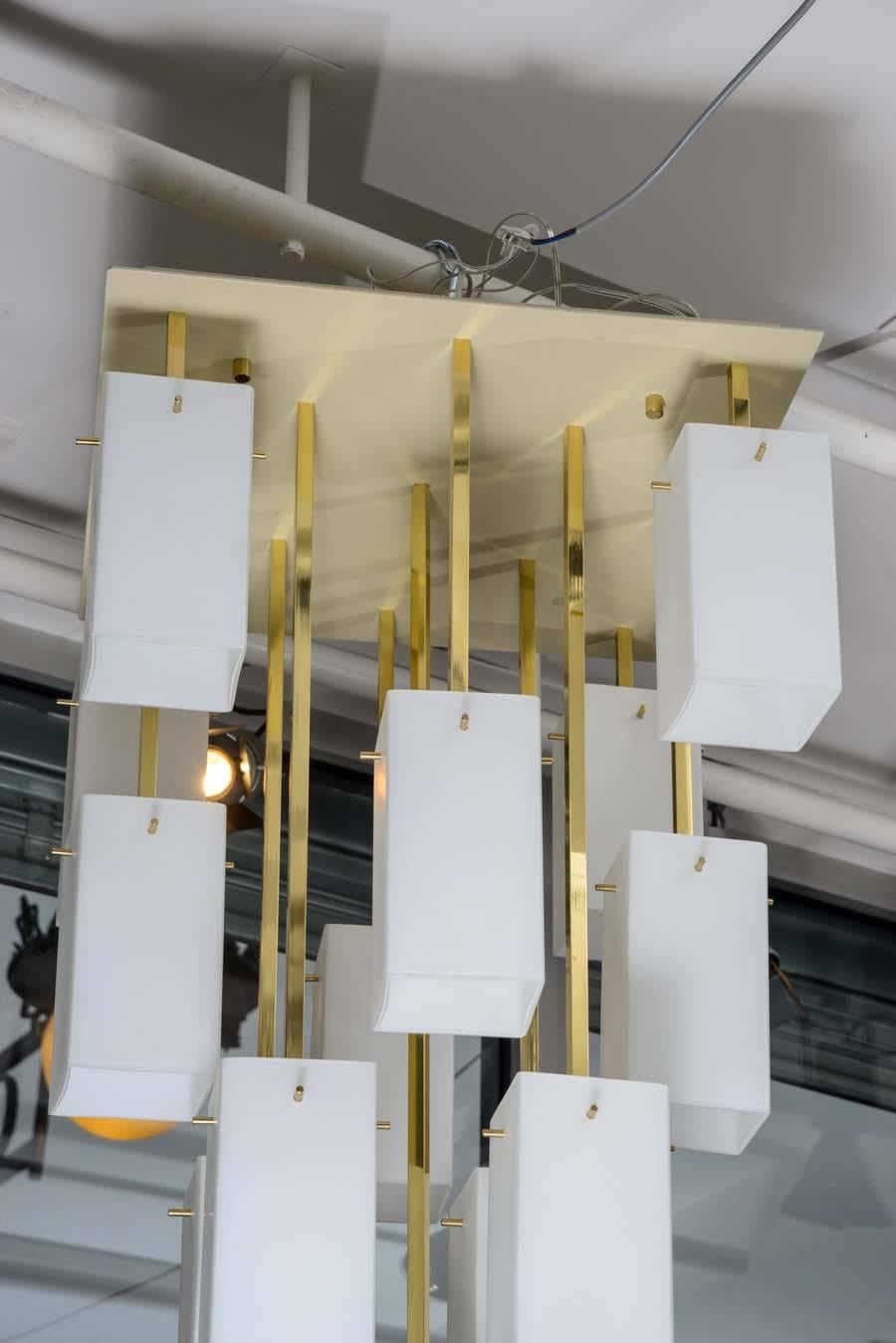 Distinguish pair of ceiling lamps made of an enameled metal square base, thirteen brass arms ended by white glass rectangles.