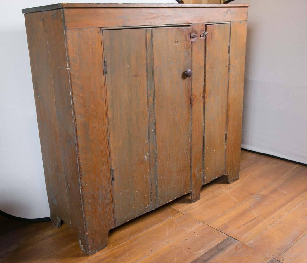 Unusual 19th century two-door country cupboard. The rectangular top over case with two random sized paneled cupboard doors opening to a shelved interior on bracket feet. From a Wethersfield, CT house. Retains old brown wash over blue painted