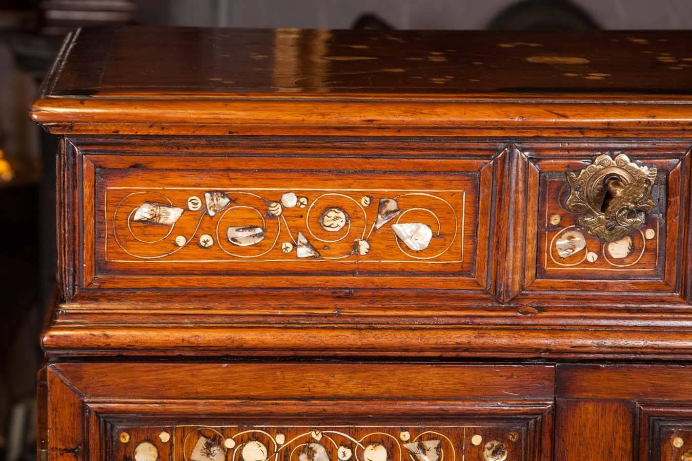 The top with hinged lid, mother-of-pearl and bone inlay and arrangement of interior cedar lined drawers; the original stand with barley twist legs 
and iron stretchers.
Dated 1632.