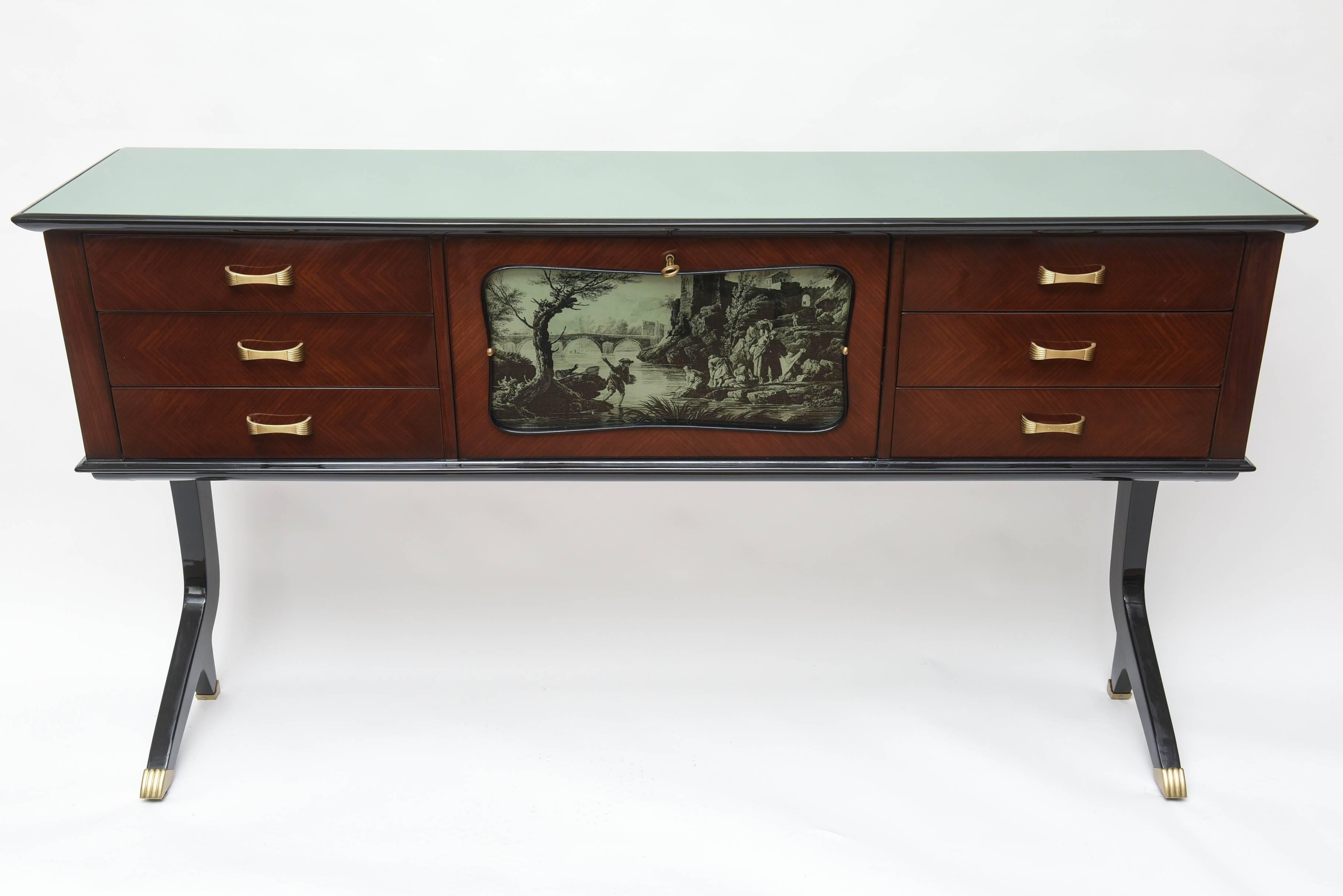 Rare and elegant Neapolitan dry bar or sideboard. Center bar with mirrored interior all original with foxing. Interior lamp. Depicting an églomisé etching of a laundry party at the riverside with a fisherman. Flanked by six drawers with brass