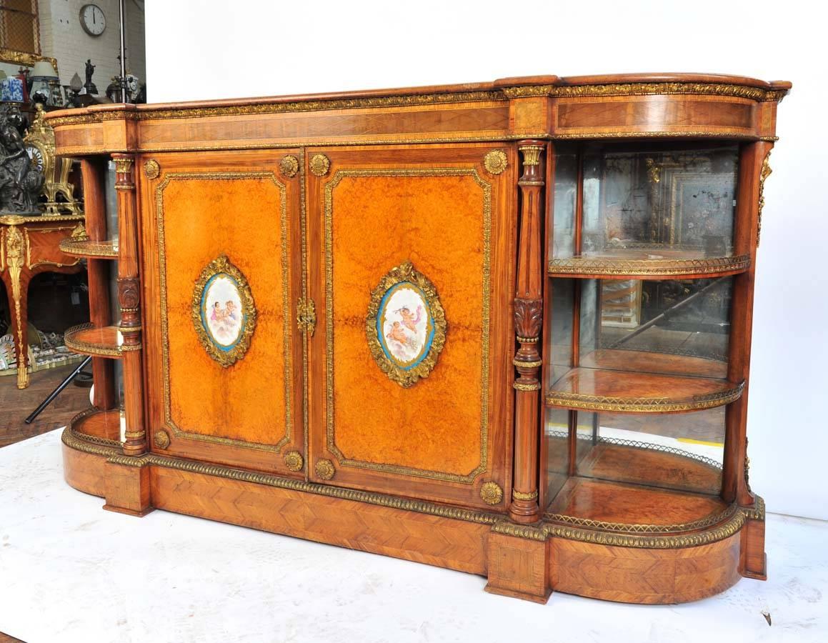 A very good quality pair of 19th century Sèvres mounted amboyna credenzas, having wonderful ormolu mounts, cross banded in Kingwood, carved columns and mirror backed open shelves to the ends.