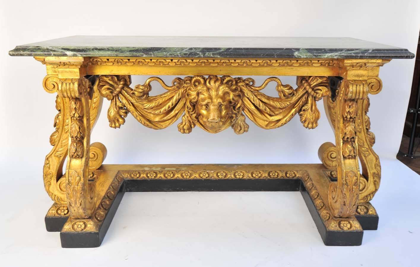 A very impressive pair of mid-19th century gilded marble-topped console tables, in the manner of William Kent, having scrolling, swag and dragoon decoration with lion masks to the centre.
