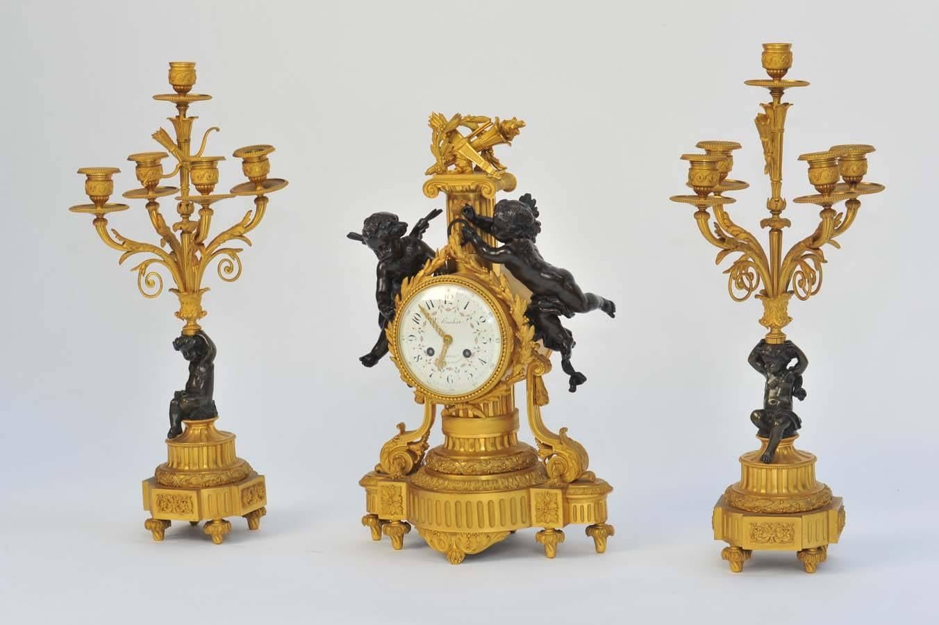 A good quality French bronze and ormolu clock garniture, having bronze cherubs mounted either side of the clock and supporting the five branch candelabra. 
Retailer; Humbert.