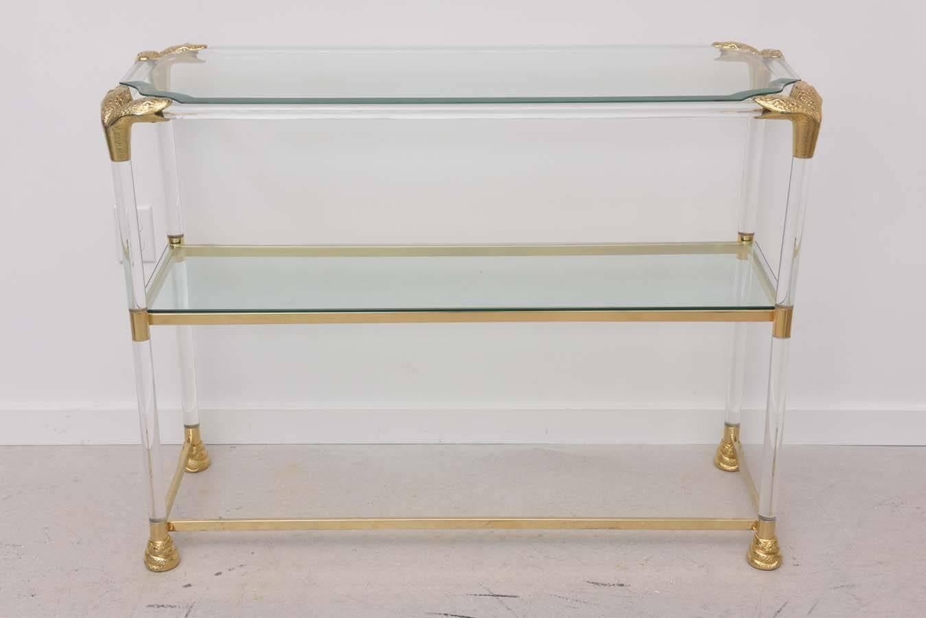 Rectangular three-tiered console table or shelf with Lucite body glass shelves and brass python heads at corners.