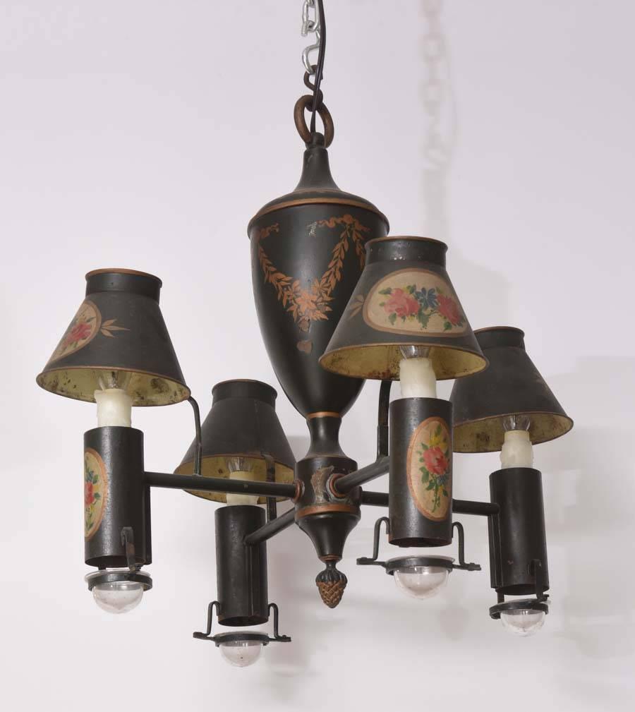 This charming four-light tole chandelier dates from the late 19th century. The piece is painted black with oval medallions decorated with floral bouquets and the central urn detailed with swaged-garlands in an antique-gold coloration.

This piece