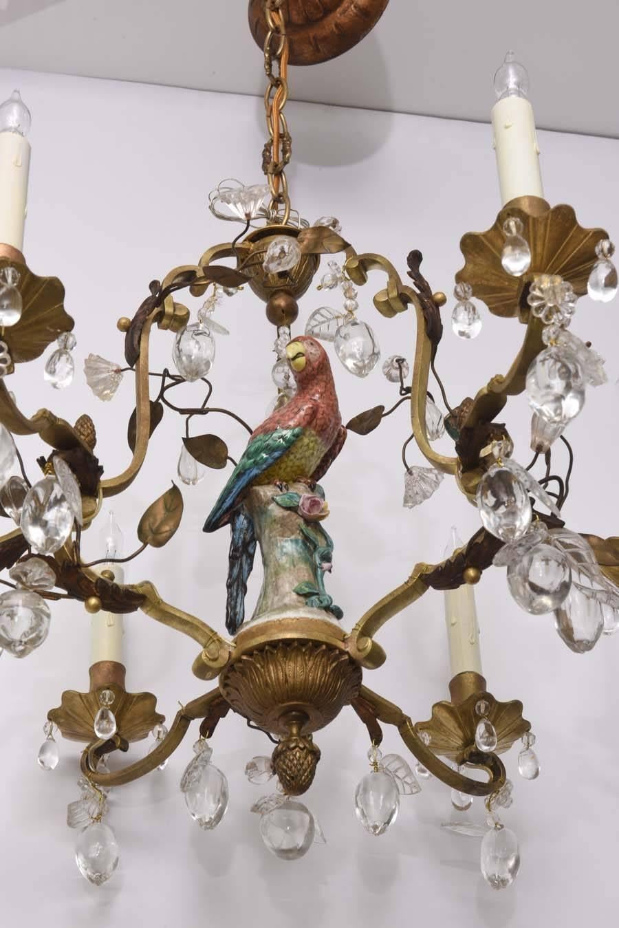 This beautiful bronze chandelier is the epitome of the Louis XV style in France with its Meissen Porcelain parrot surrounded by floral and fruit shaped crystals. The piece dates to the late 19th and early 20th century.

Note: The canopy show at an