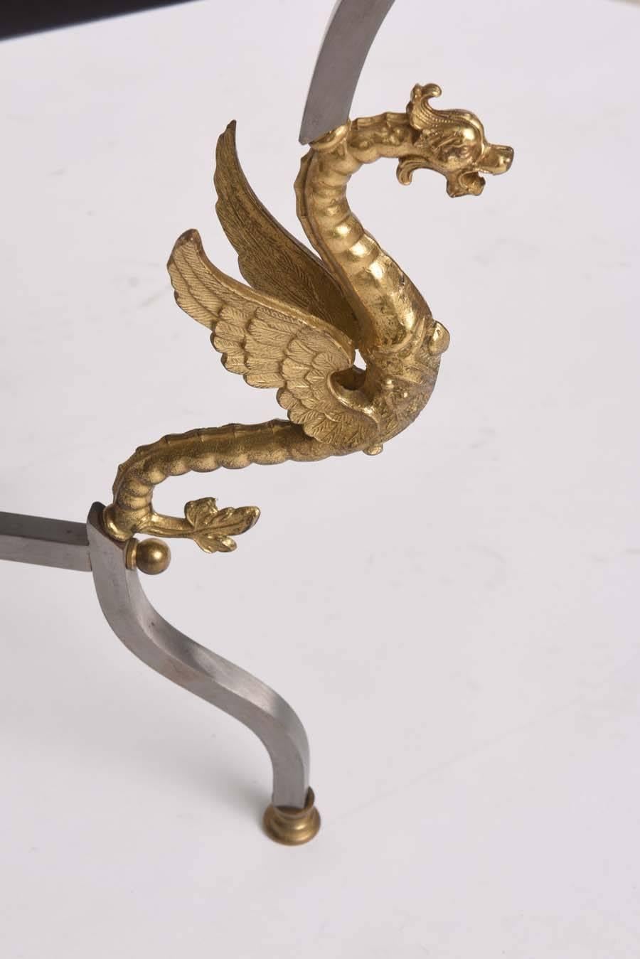 This handsome cocktail table was made by the iconic Trouvailles Furniture Company that was established in 1960. 

This piece is very much in keeping with pieces designed by Maison Jansen with its high-quality brass winged dragon castings, inlaid