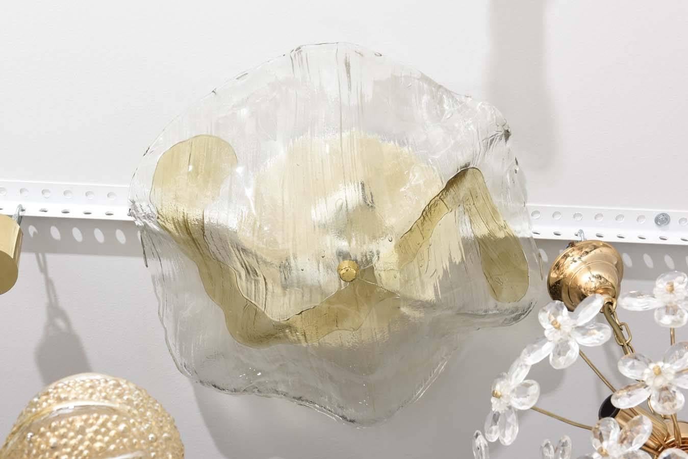This handsome Mid-Century Modern chandelier was created in the 1960s by the iconic German firm of Kamer Lighting. The stylized free-form globe is the underside of a flower and is in clear and tan colored glass.

The finial that holds the globe in