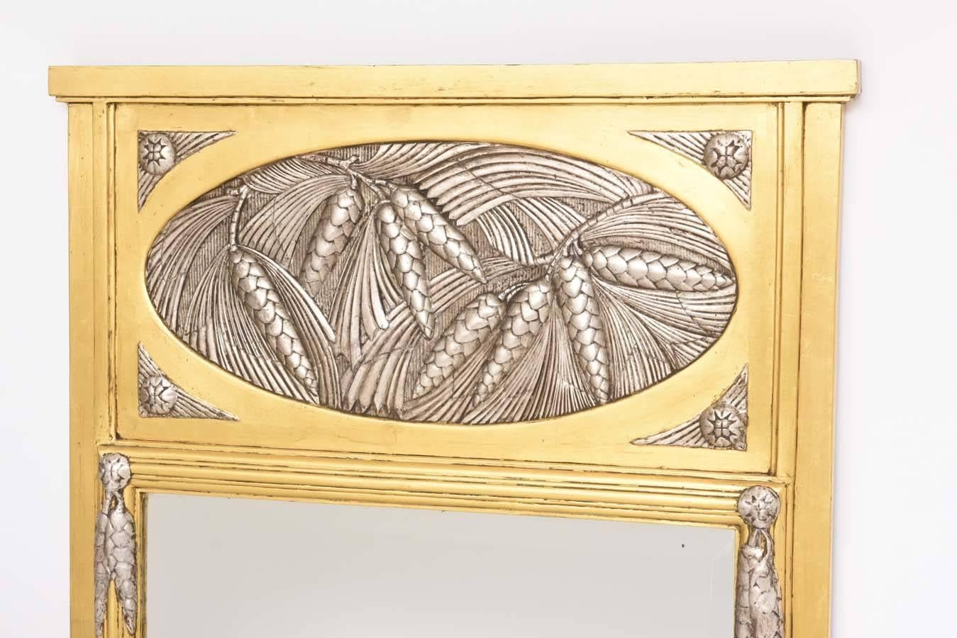 This stylish Art Deco trumeau mirror dates from the 1930s and was purchased in France. The piece is simple and elegant with its pine cones and needles in a soft silver leaf medallion and accents. The gold and silver leaf has mellowed to a soft