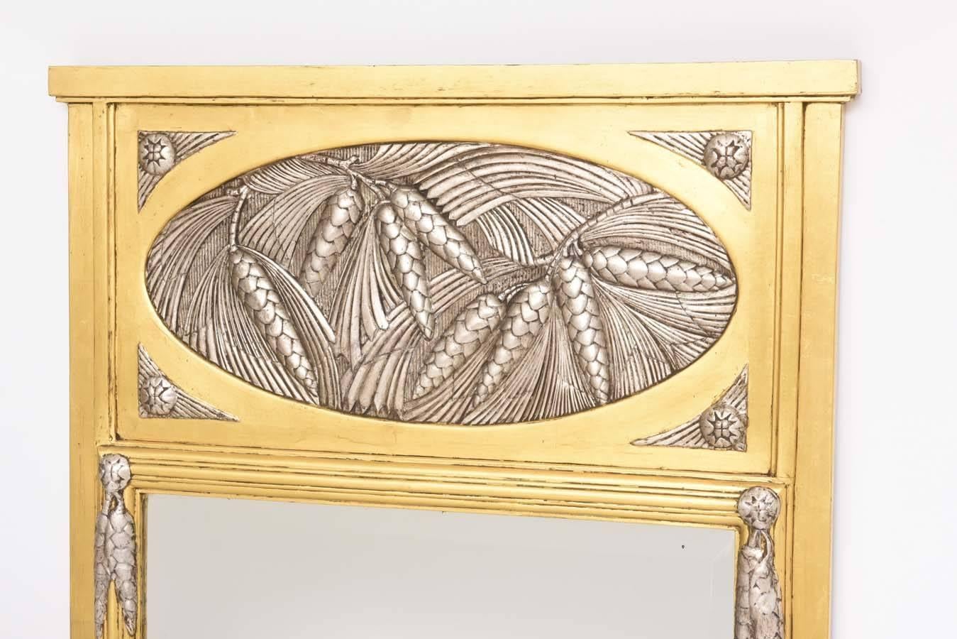 Cet élégant miroir trumeau Art déco date des années 1930 et a été acheté en France. La pièce est simple et élégante avec ses pommes de pin et ses aiguilles dans un médaillon et des accents de feuilles d'argent doux. Les feuilles d'or et d'argent se