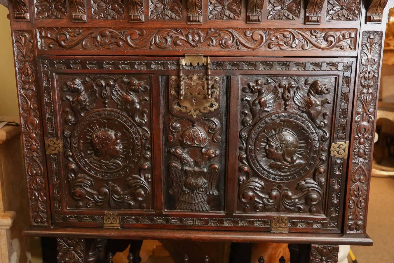 Antique Spanish desk made of dark walnut with extensive carvings.
Raised on carved legs in a barley twist pattern. The front door of the
desk is carved with two heads in an elaborate design. The door drops
down to an opening which exposes the