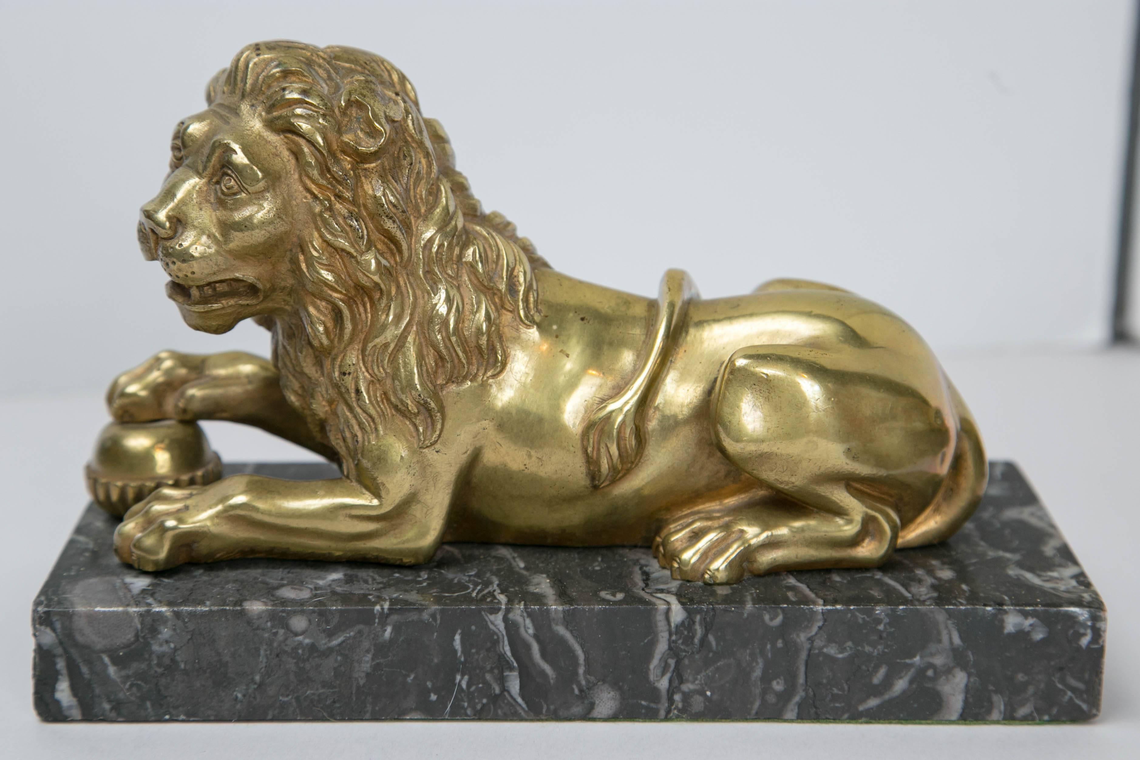A rare pair of gilt bronze Medici lions resting on marble base. Each lion has a paw resting on a ball.