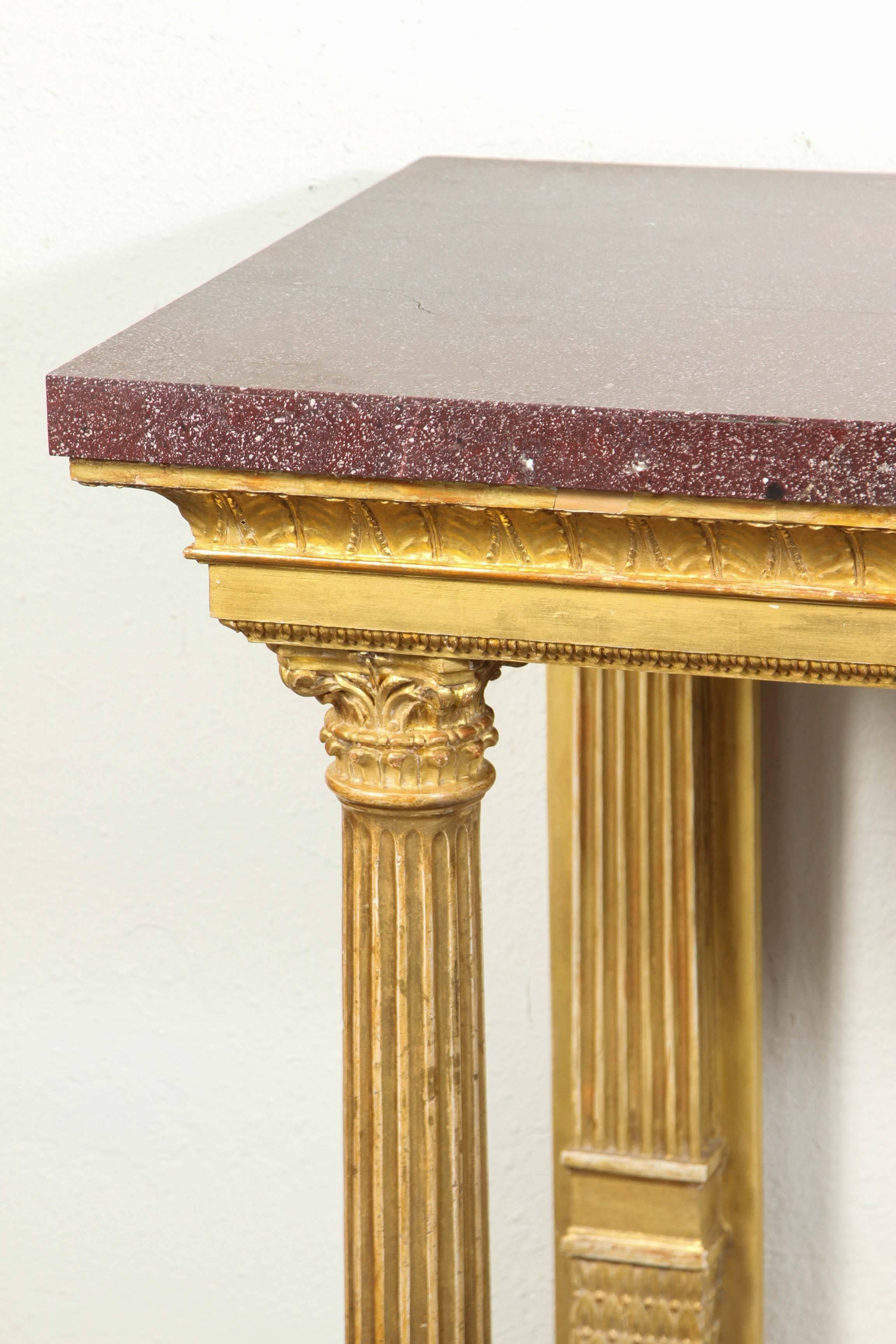 Pair of fine, hand-carved, circa 1830, gilt-wood, Florentine console tables. Porphyry veneered tops sit above a tiered, plinth supported by fluted, Corinthian columns. 