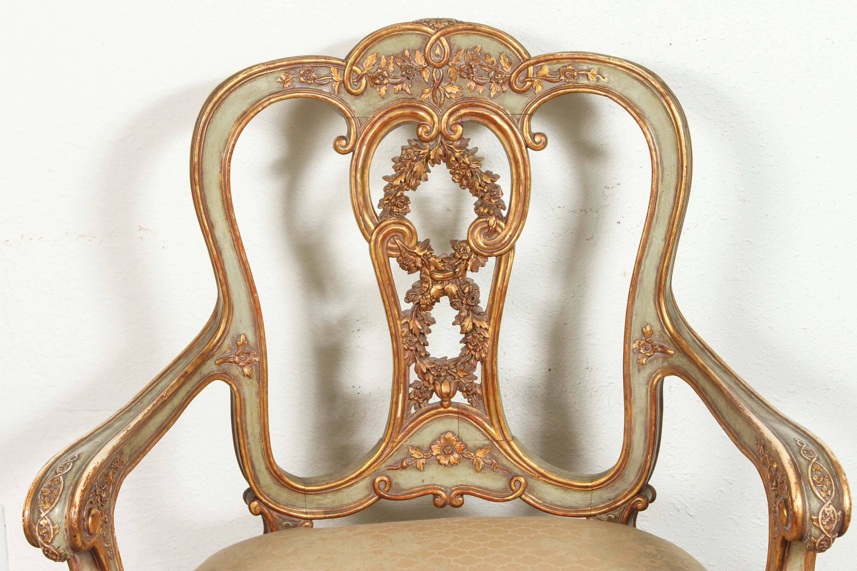 Two, hand-carved and painted, parcel-gilt, Venetian armchairs with pierced splat featuring carvings of fruit laden wreaths.